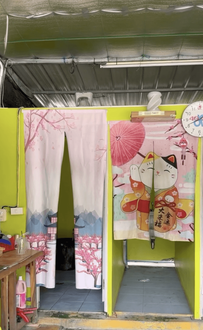 man in blue t-shirt and white floral skirt holding black smartphone while sitting on sidewalk