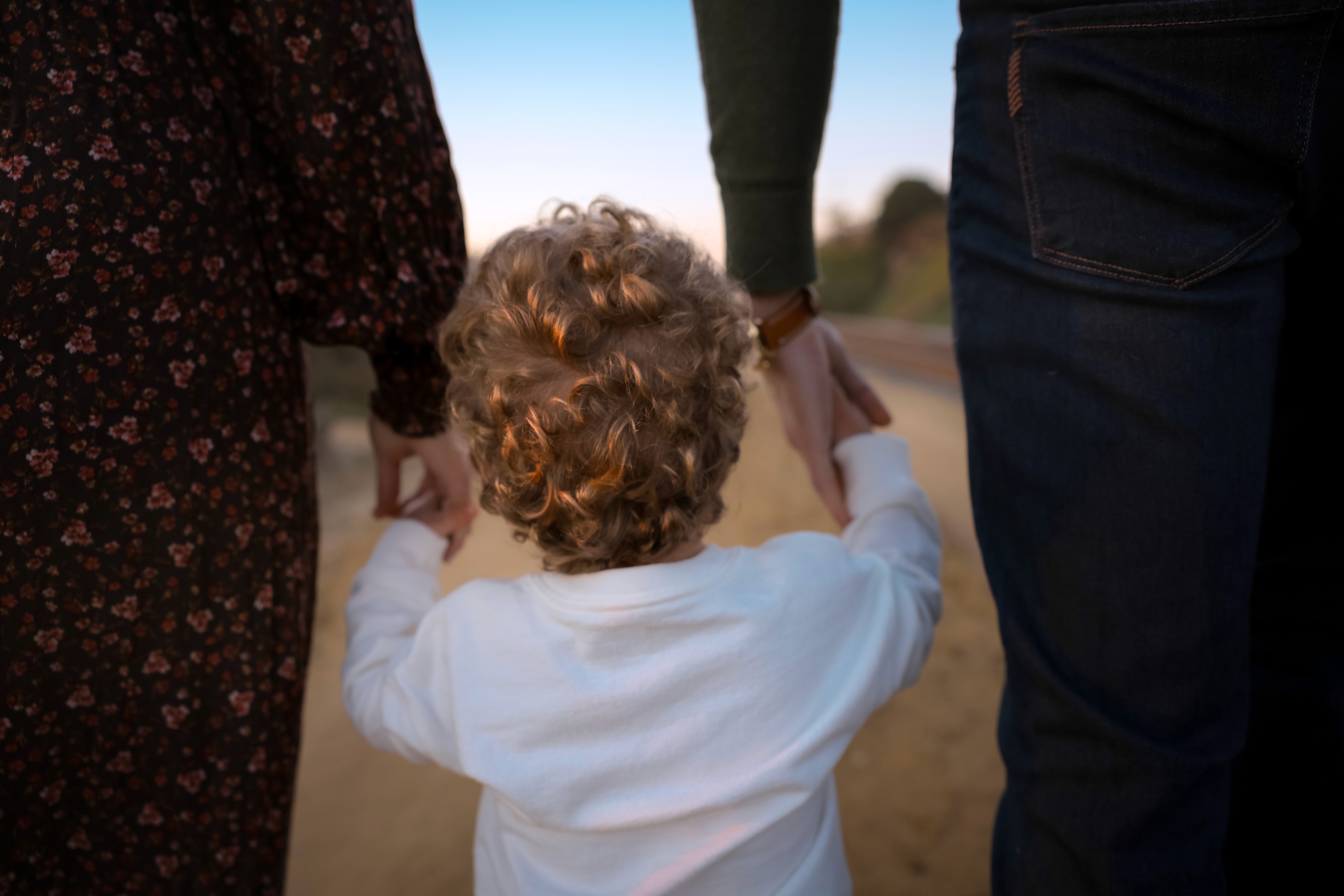 Family walking along the coastal trail, holding hands near sunset.