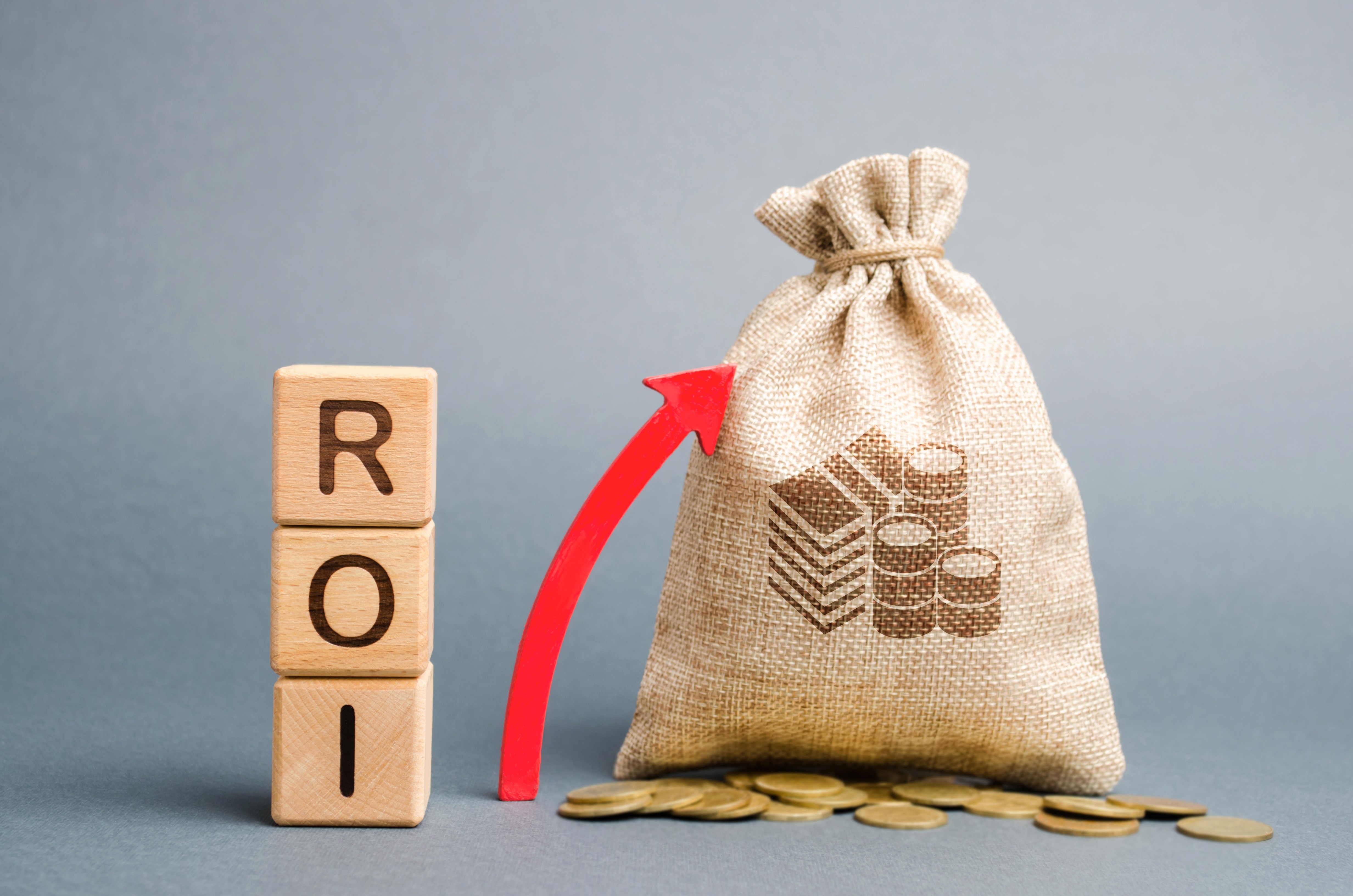 Wooden blocks spelling ROI next to a money bag with an upward red arrow, representing the return on investment a service business can expect from a structured marketing system