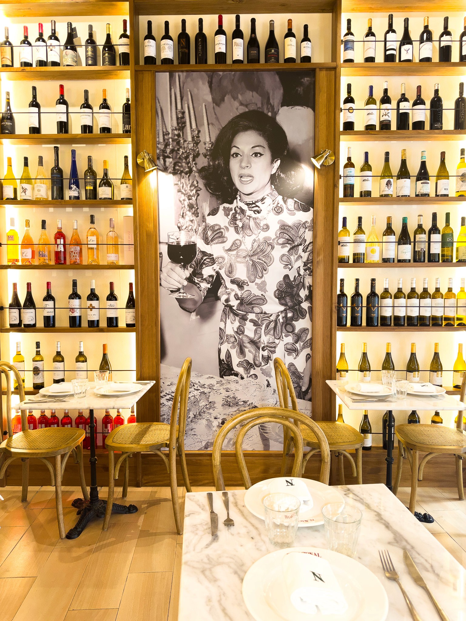 Wooden outdoor table set with multiple plates of food, including dips, salads, potatoes with cheese, and glasses of water, with hands reaching in to eat.