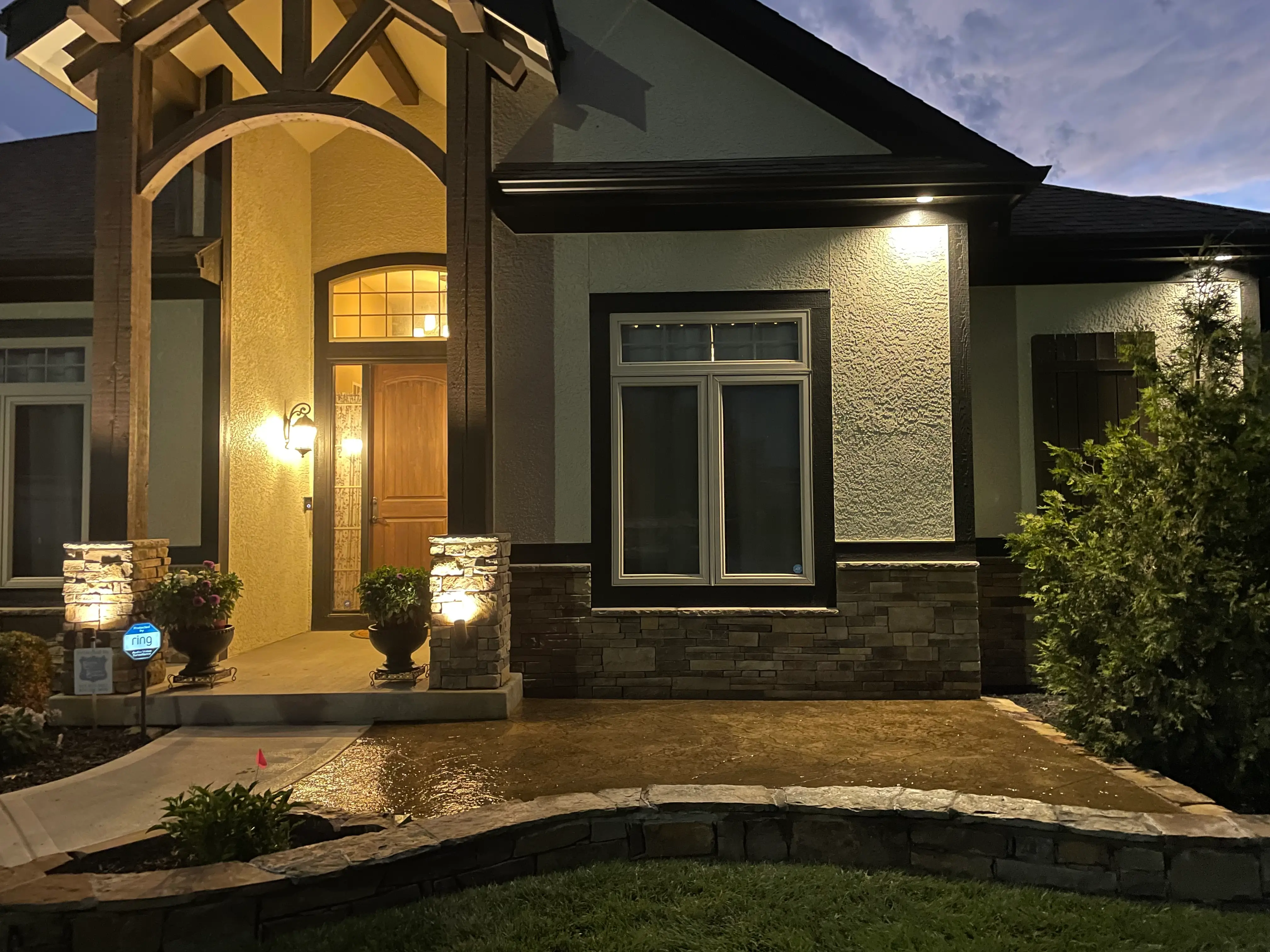 A dusk image of a stamped concrete front patio made to look like stone.