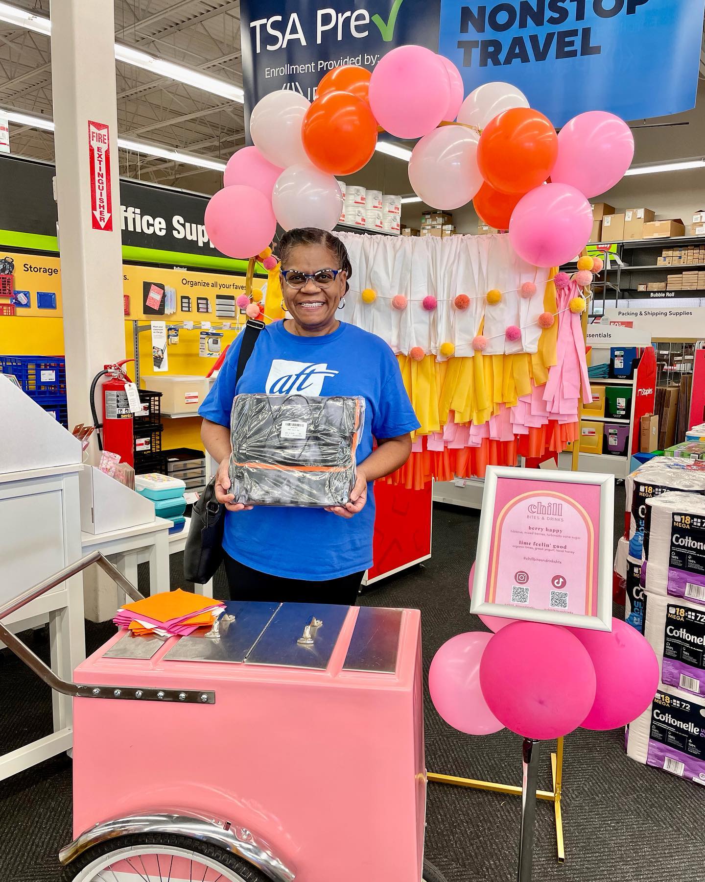 A woman in a Staples score in front of the Chill Bites and Drinks cart and balloons in the background