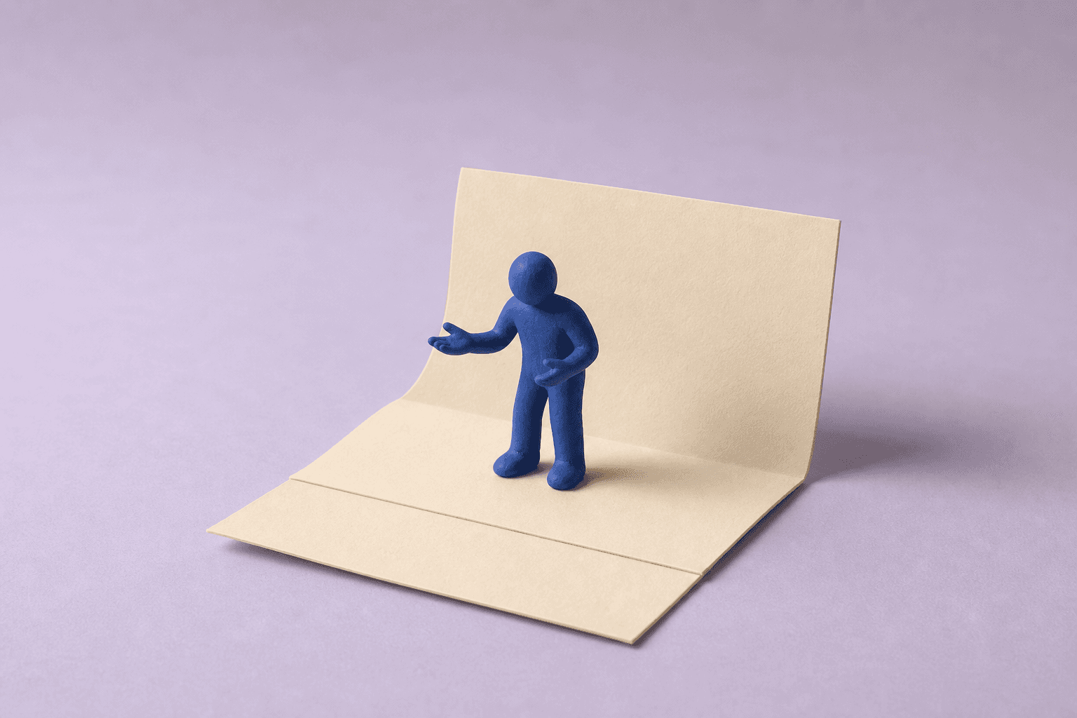 A blue clay figure gestures while standing on an open cream paper stage.