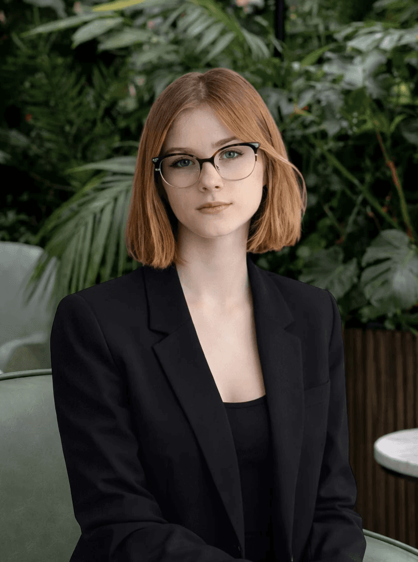 Casual studio portrait of a bearded man with curly hair in a white shirt, arms crossed, on a light gray background.