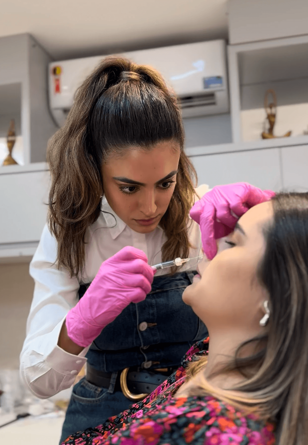 A circle of people sitting cross-legged, meditating with hands in a prayer position. Soft, warm lighting.