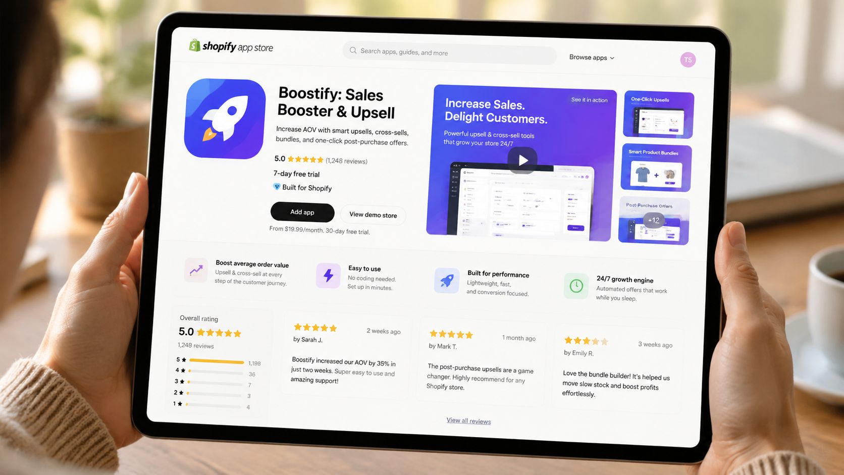 A person holding a tablet displaying the Boostify Shopify app store page with reviews and marketing features.