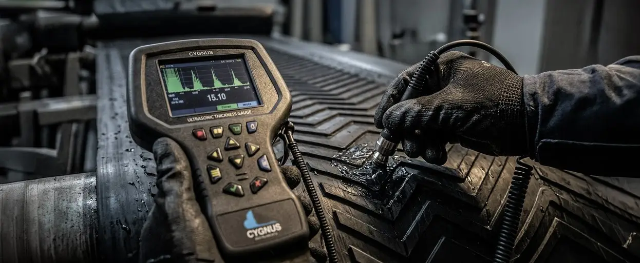 Glospech technician using Cygnus 1 EX intrinsically safe ultrasonic thickness gauge to measure wall thickness through rubber lagging on mining conveyor pulley