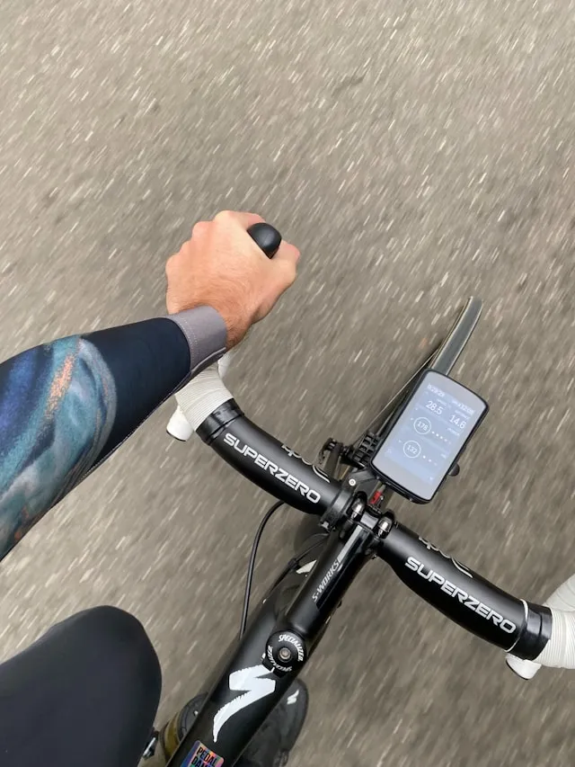 Close-up of a cyclist’s hands on handlebars with a bike computer during a ride