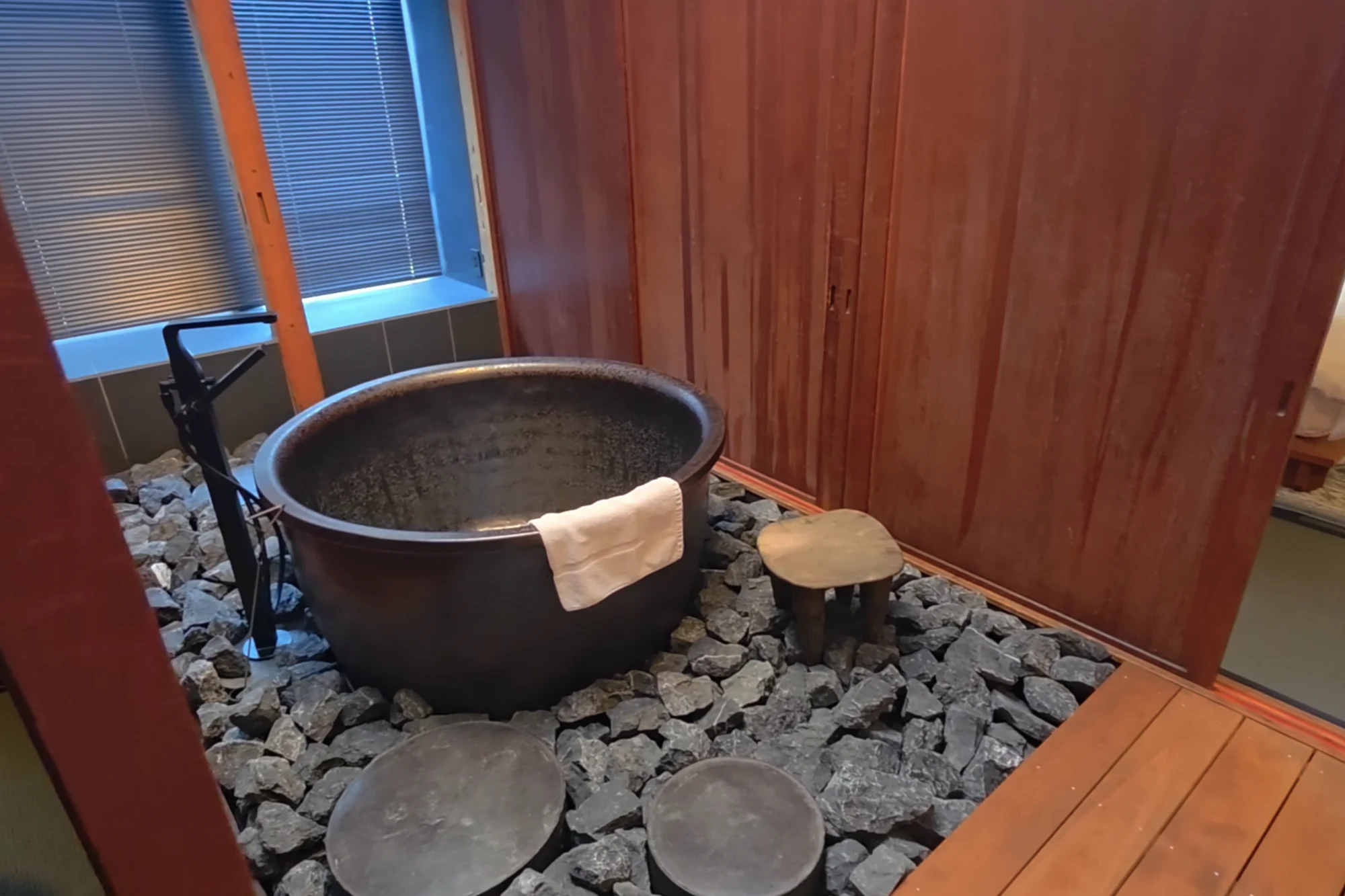 A single soaking tub on a small stone terrace beside a guest room in a Kinosaki inn.