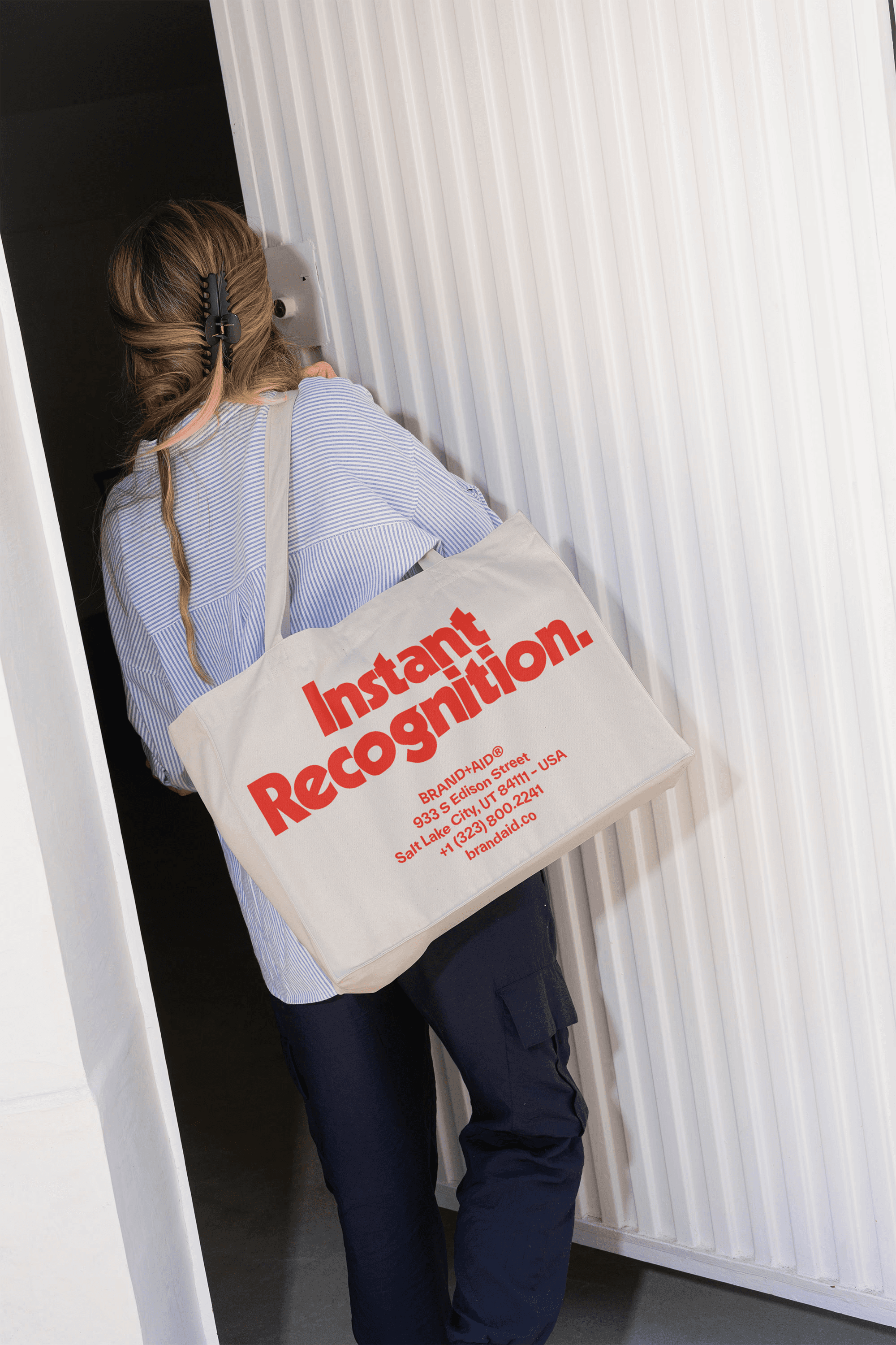 Person walking through a doorway with a brand BRAND+AID® tote bag