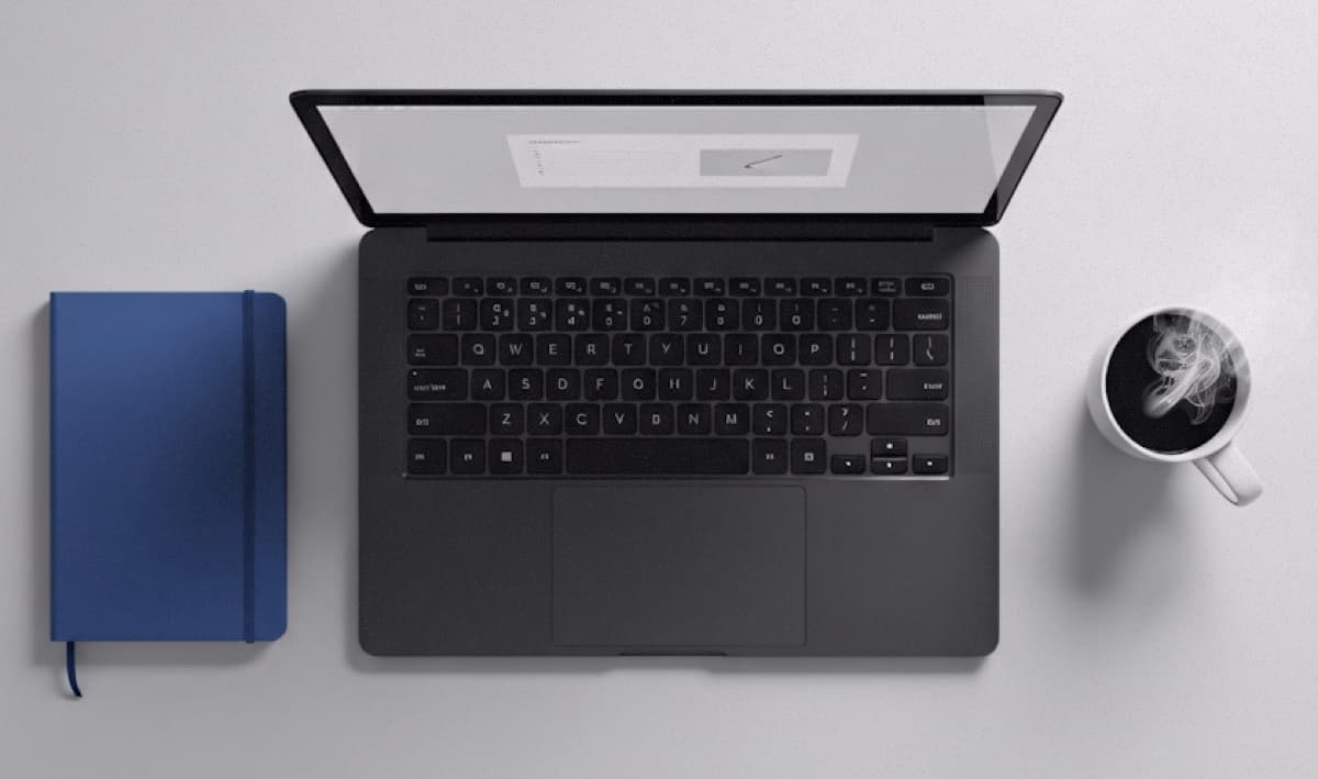 Minimalist desk with notebook, laptop and coffee mug