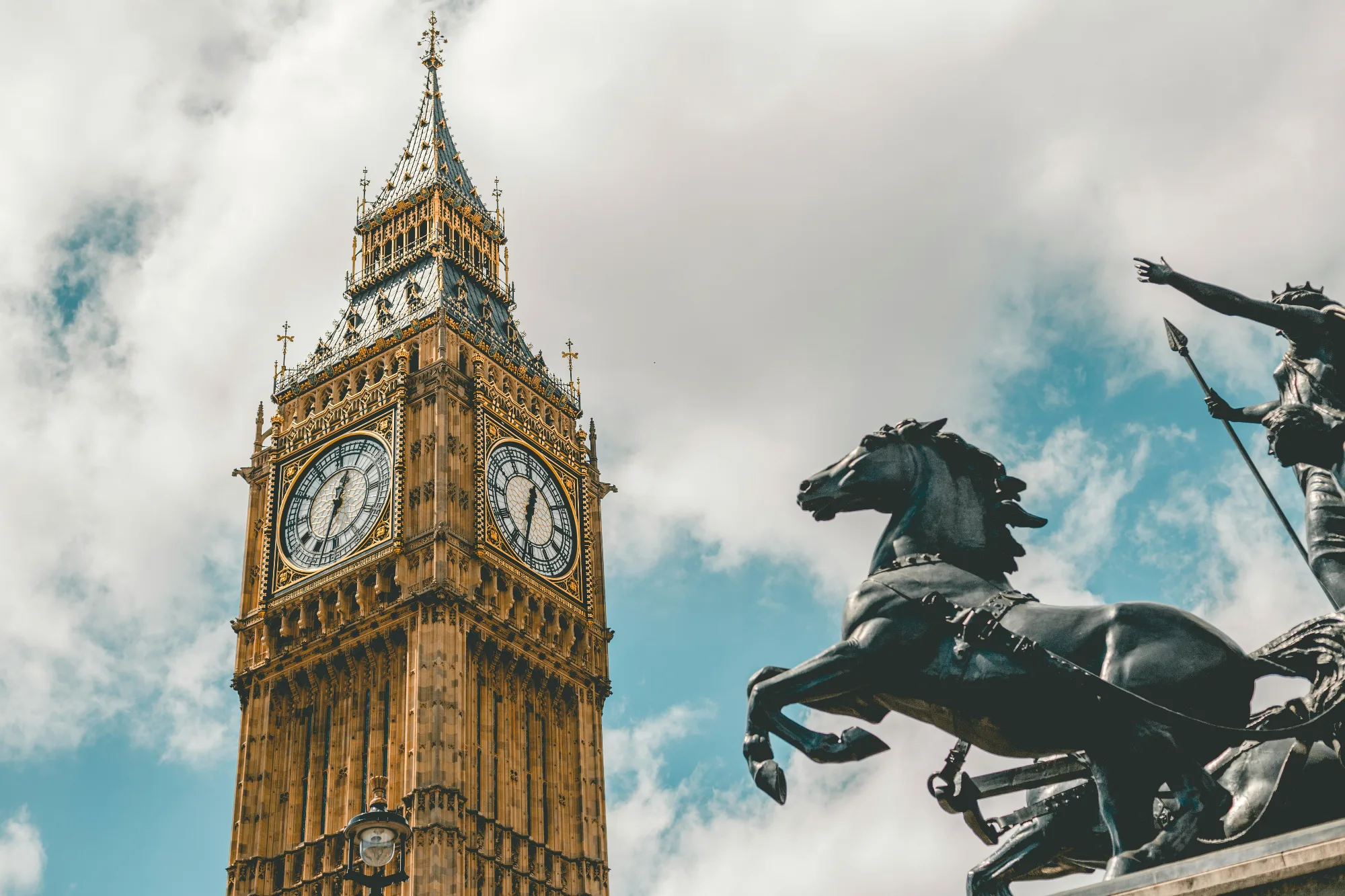 Big Ben viewed from the ground, with a cloudy blue sky in the background.