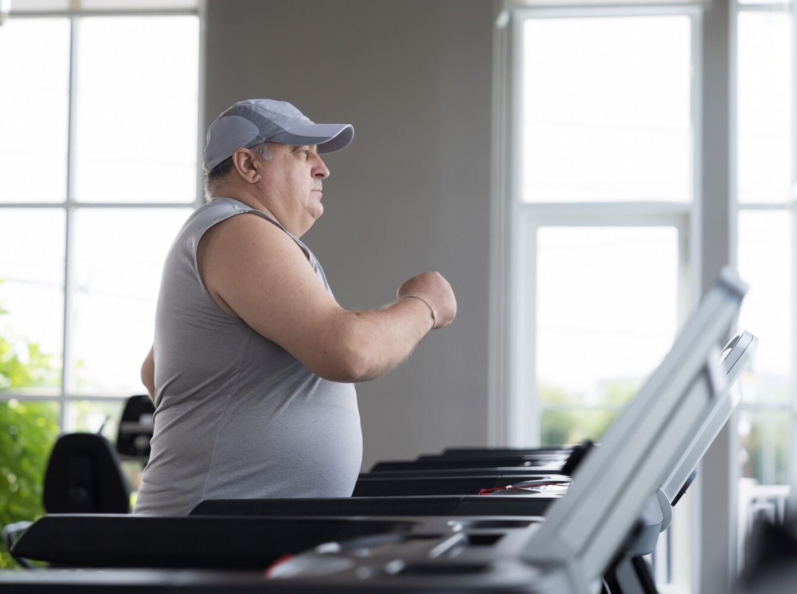 overweight older man at gym running the best treadmill speed and incline for weight loss
