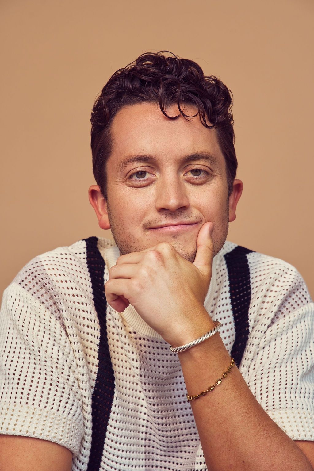 Portrait of a laughing person with curly hair wearing a white shirt