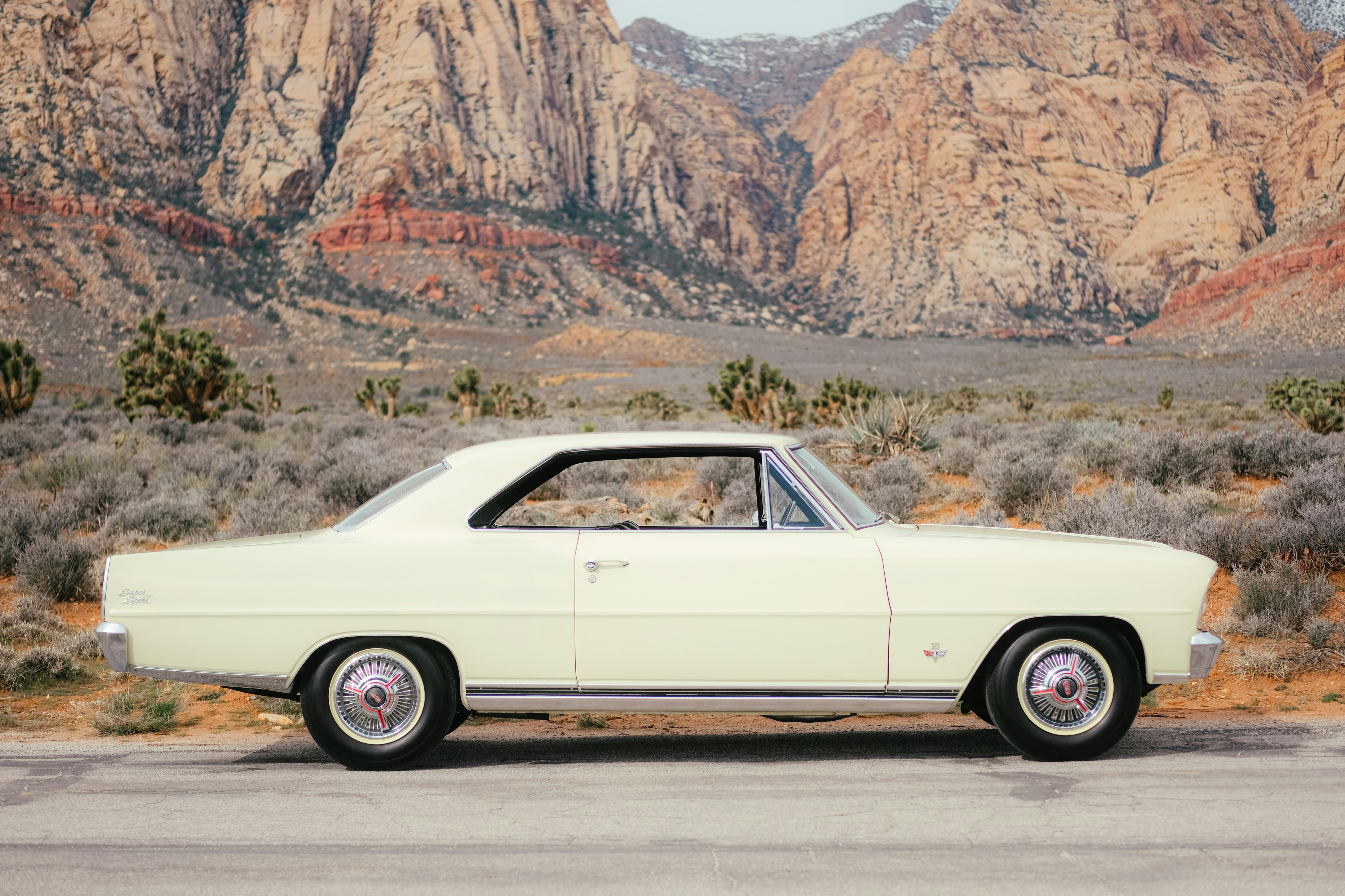 Classic cream car parked before desert mountains