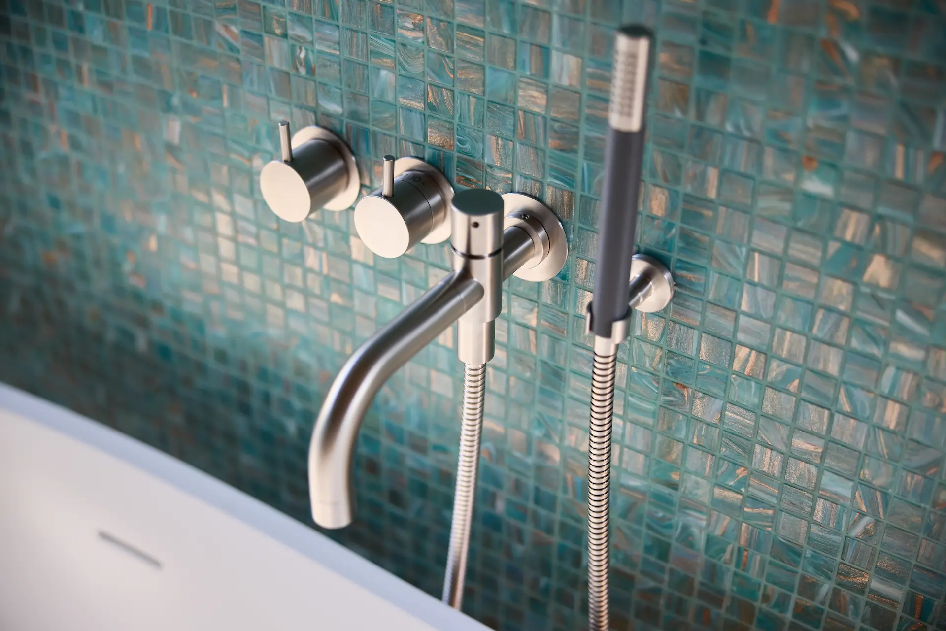 View of the master bathroom's wall-mounted tub faucet, showcasing sleek design and modern luxury in this Eichler home remodel. Photo by Todd Huge.