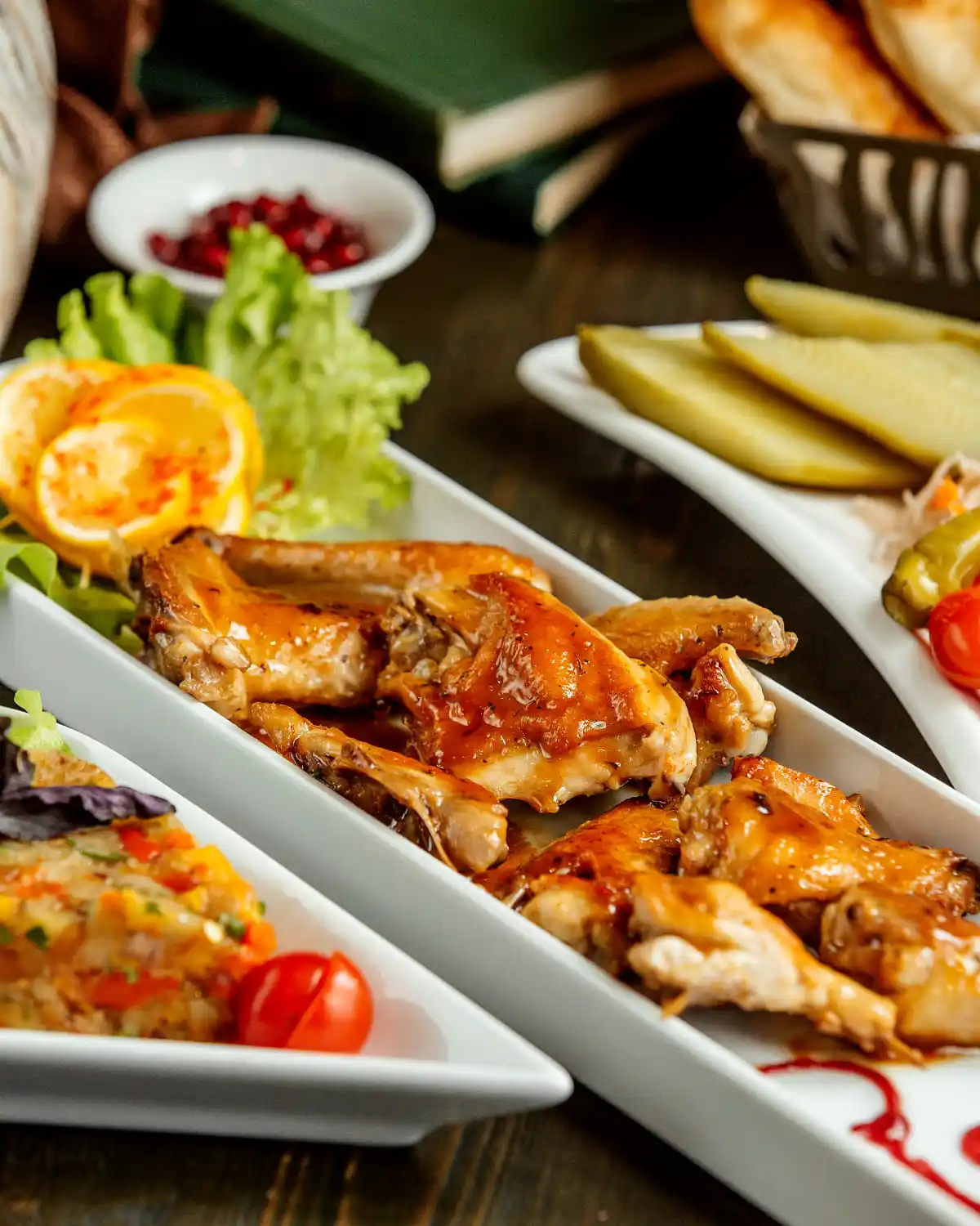 Glazed chicken pieces on a white plate with lettuce and orange.