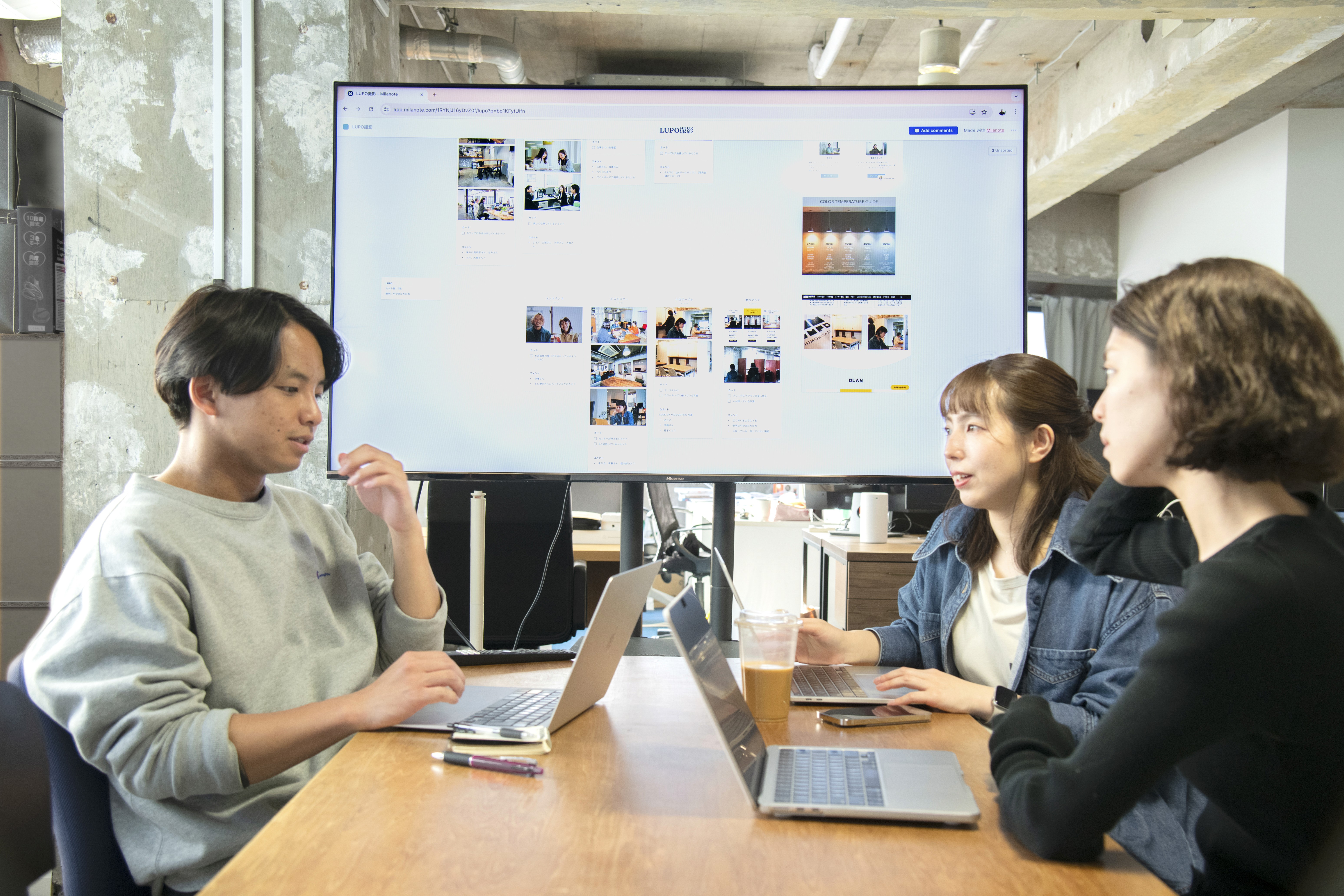 Business team collaborating in meeting room with whiteboard and notes on wall and table.