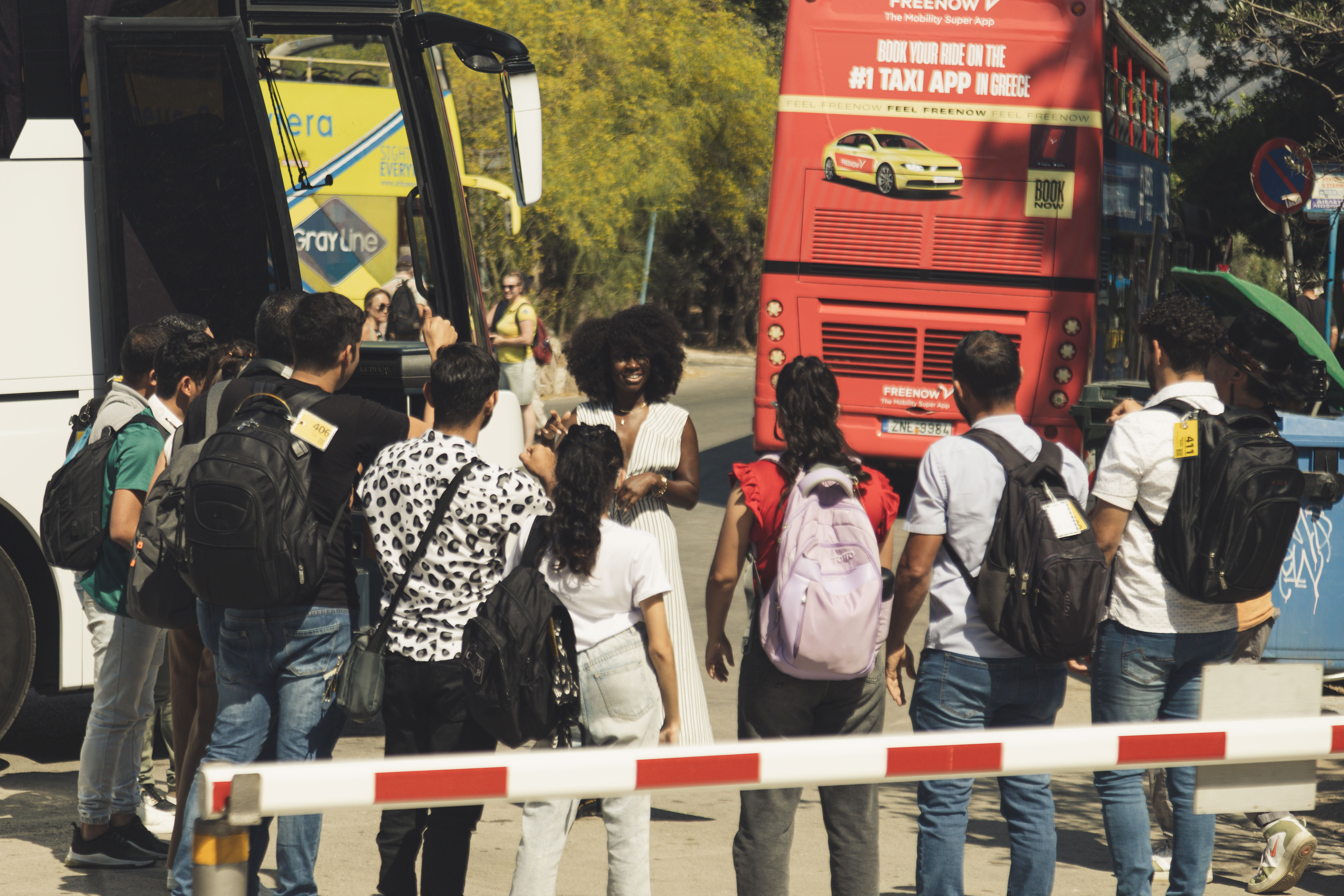 Natasha Ofili (a dark-skinned Black woman) greeting the Coros de Manos Blancas (the Venezuelan White Hands Choir) outside their bus upon arriving at The Herodion in Greece. 