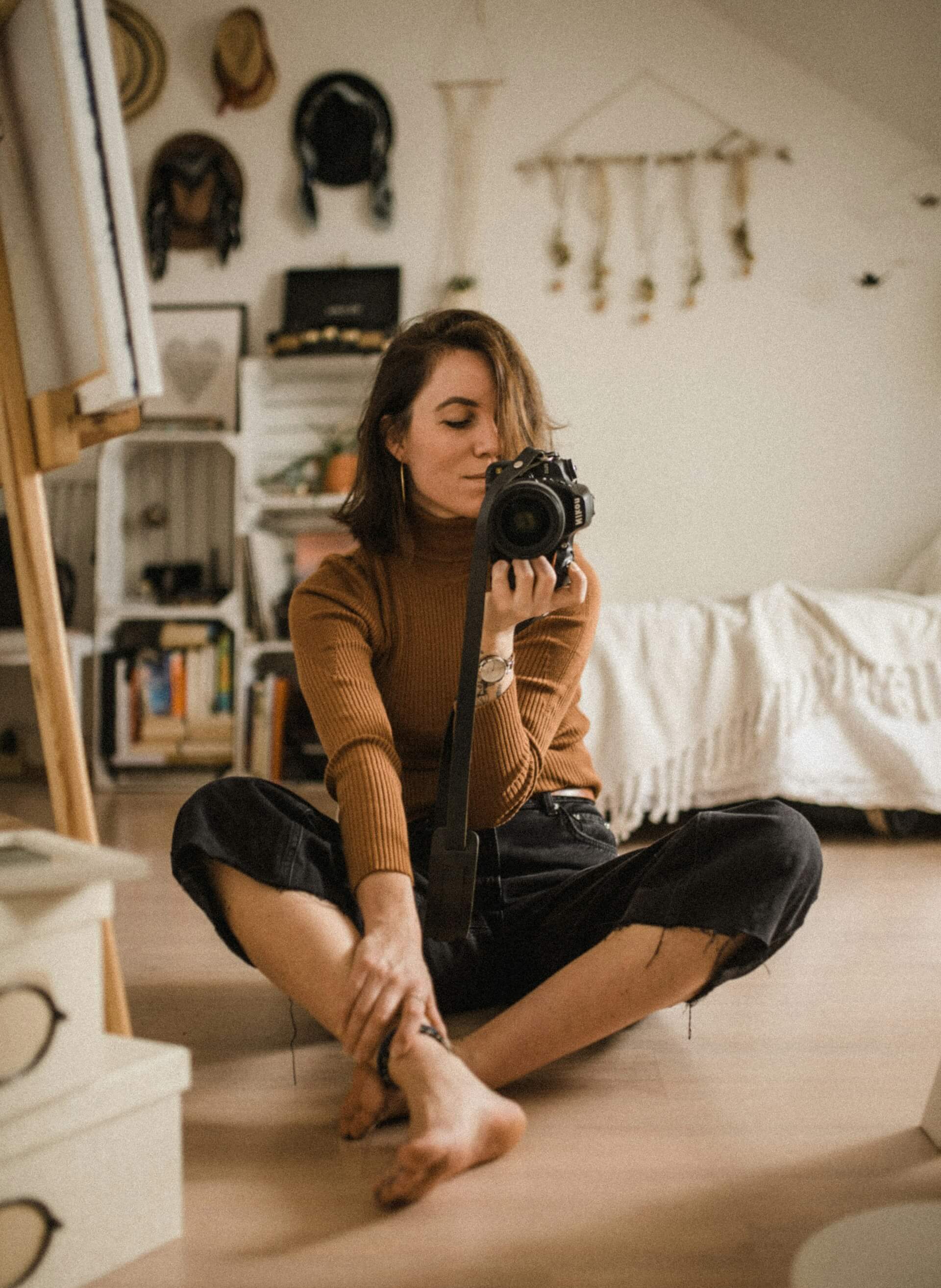 A woman seated on the floor, capturing a photograph with her camera