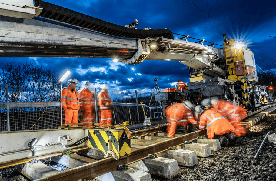 People working on a railway platform under bright lights.