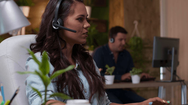 Photo of a customer service rep, with a headset in her ears, speaking