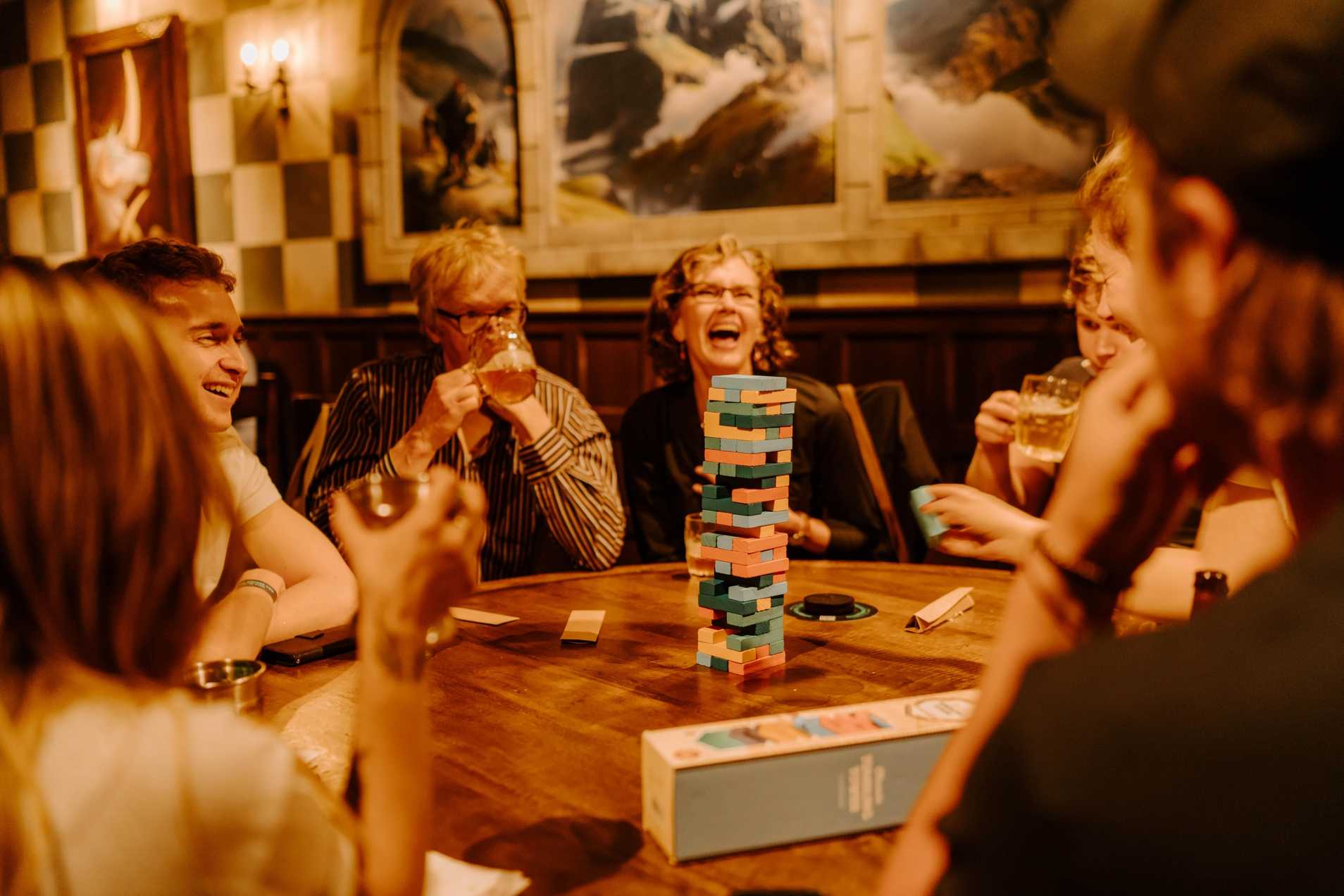 family enjoying jenga, laughing and playing in well lit tavern