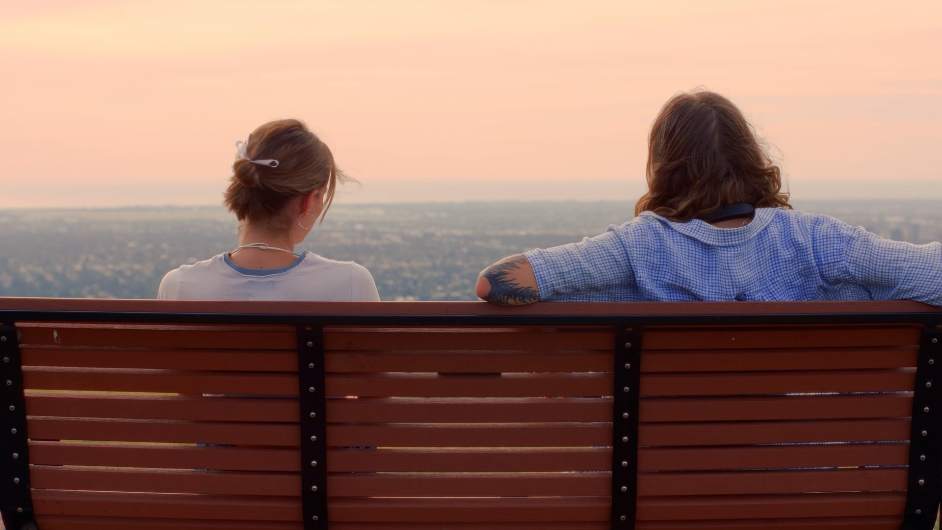 Two filmmakers operate a large camera in a dimly lit studio, wearing headphones and focused intently on the screen, conveying concentration.