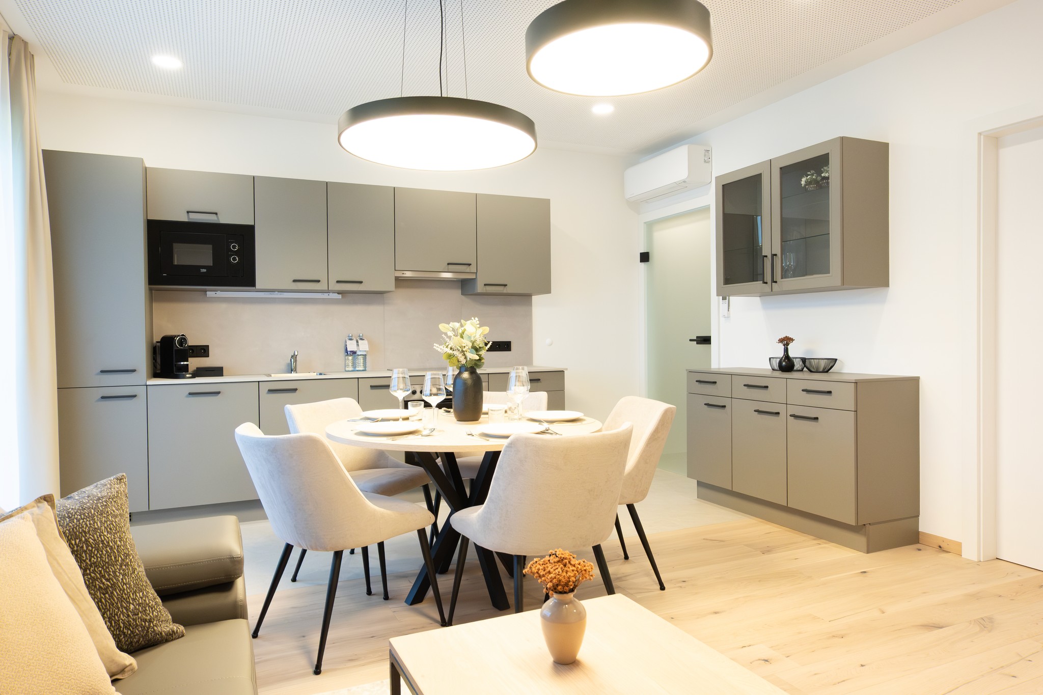 Moderne Küche mit Essbereich. Graue Schränke, Esstisch mit Stühlen, Wohnraum, helle Wohnung