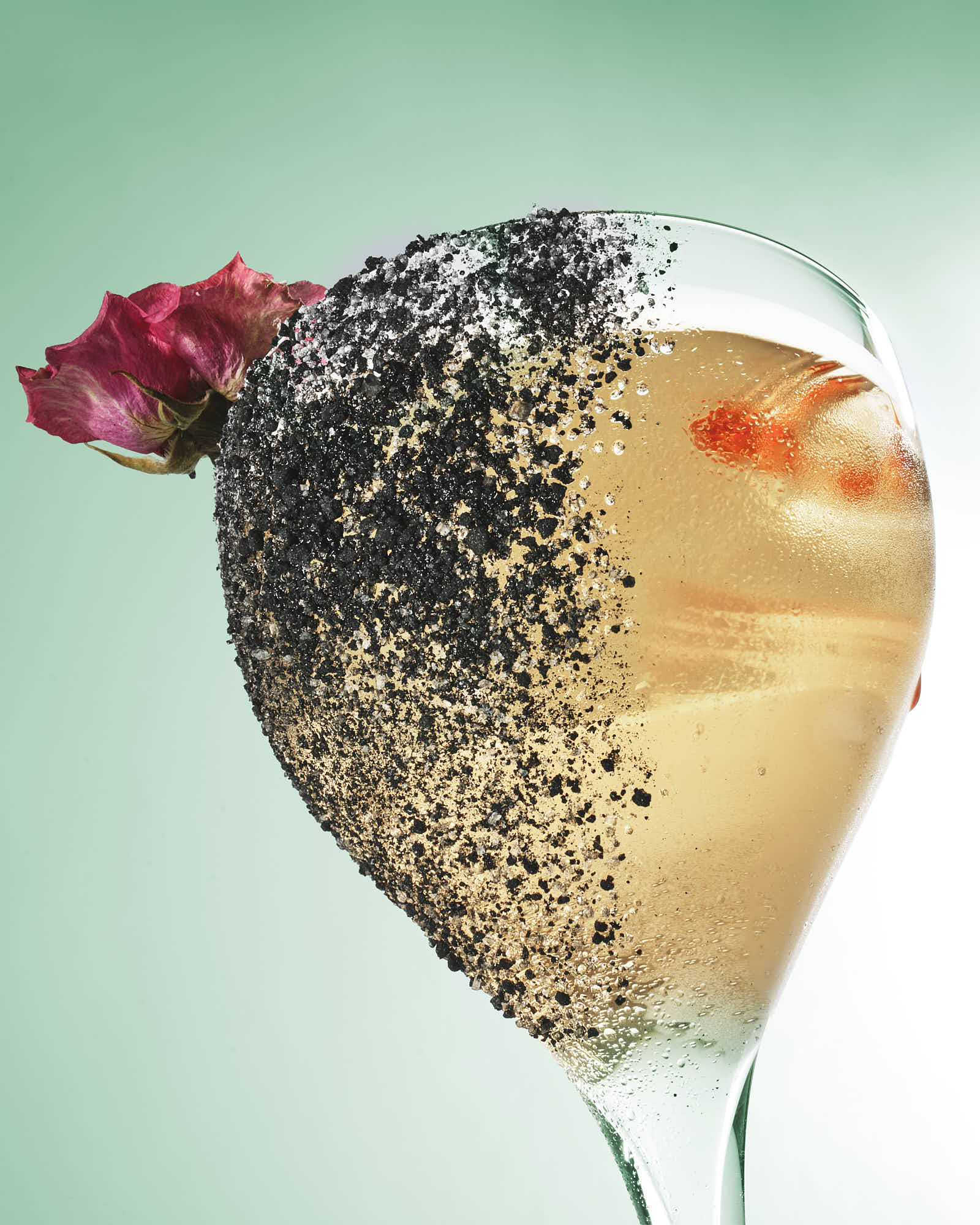 A unique cocktail garnished with a strawberry, served in a glass against a soft green background.