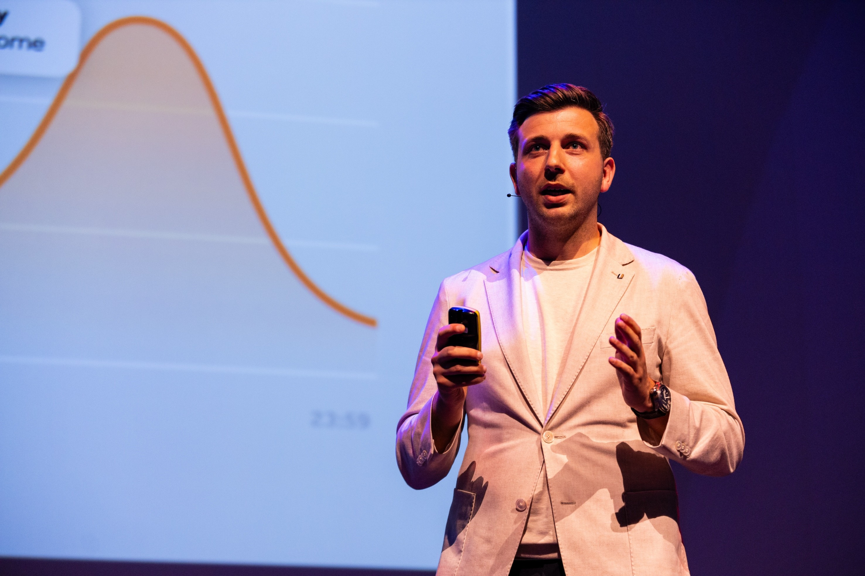 A smiling woman with her arms crossed, standing against a dark green background. She has long, dark hair.