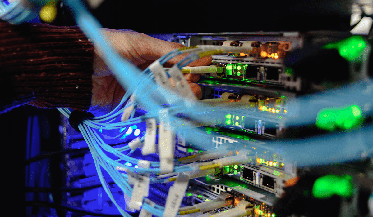 Mão de um técnico de dataecnter manuseando fibras óticas