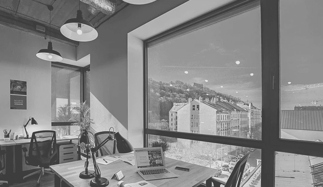 Modern red brick apartment or office building viewed from below against a blue sky, showcasing its geometric architecture with evenly spaced windows and balconies.