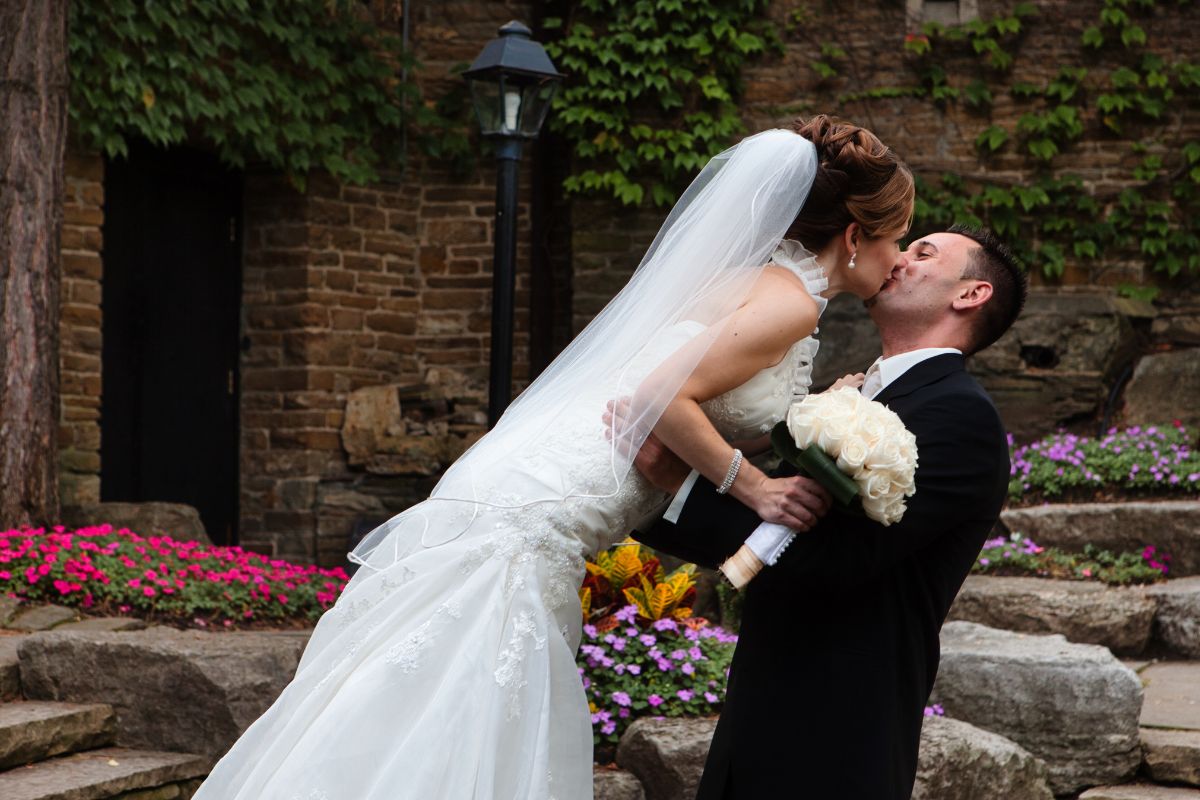 A bride and groom sharing a joyful dance together outdoors, surrounded by natural scenery and a romantic atmosphere.