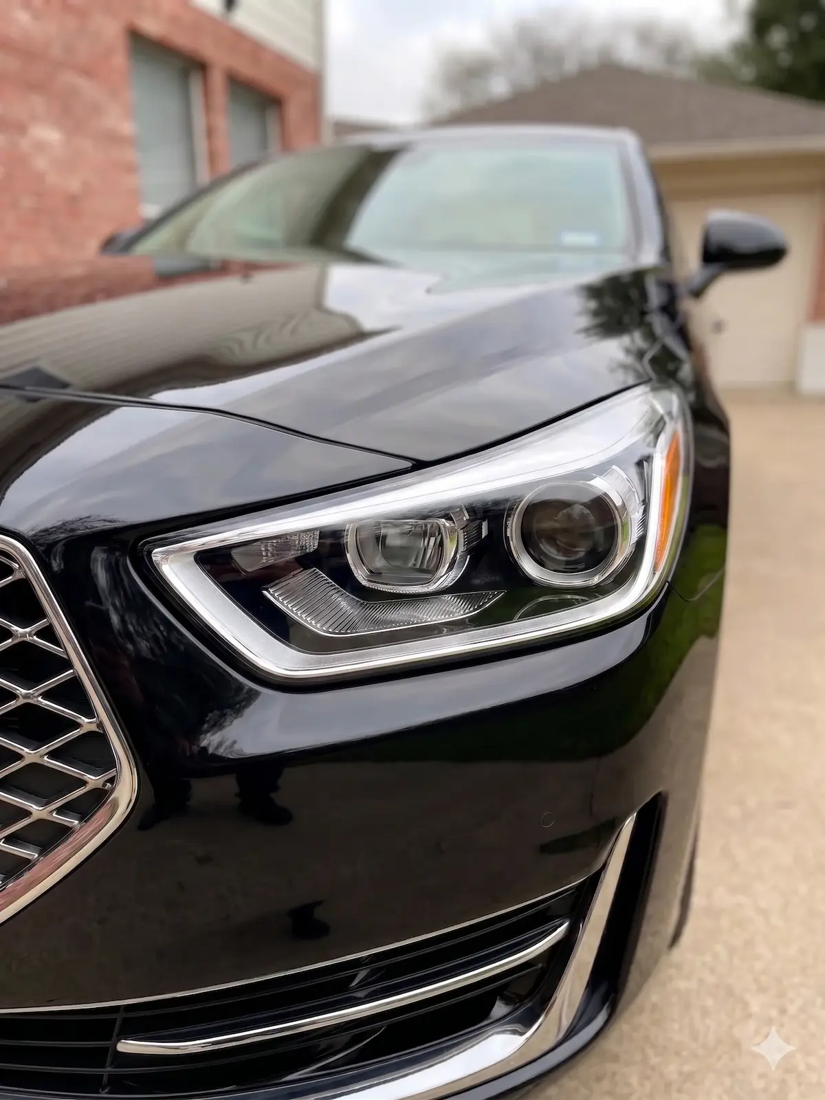 Professional headlight restoration on a black Genesis G90 in Houston, removing oxidation and yellowing for a factory-new finish.