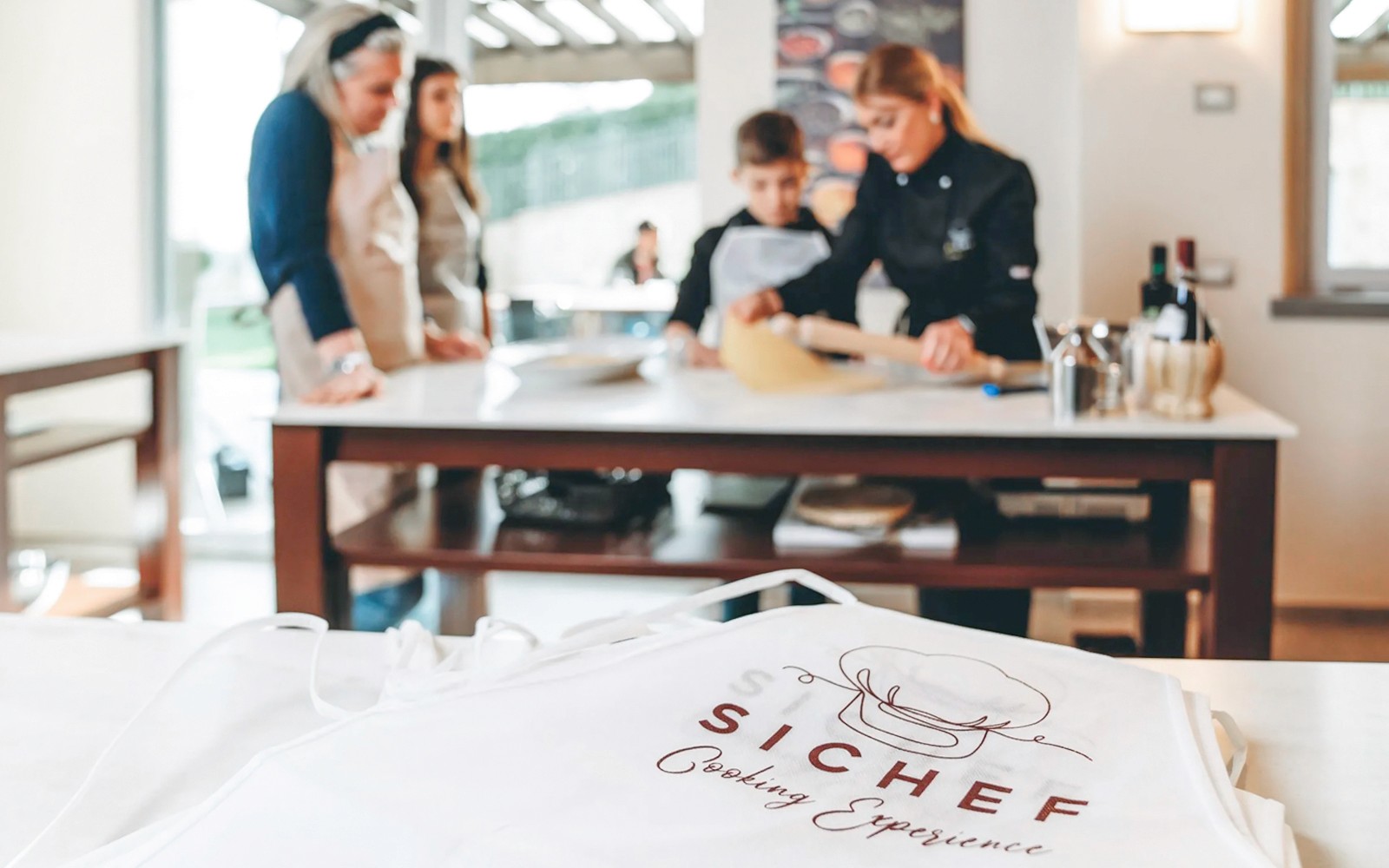 Teilnehmer des Kochkurses stellen unter Anleitung eines Küchenchefs frische Pasta her.