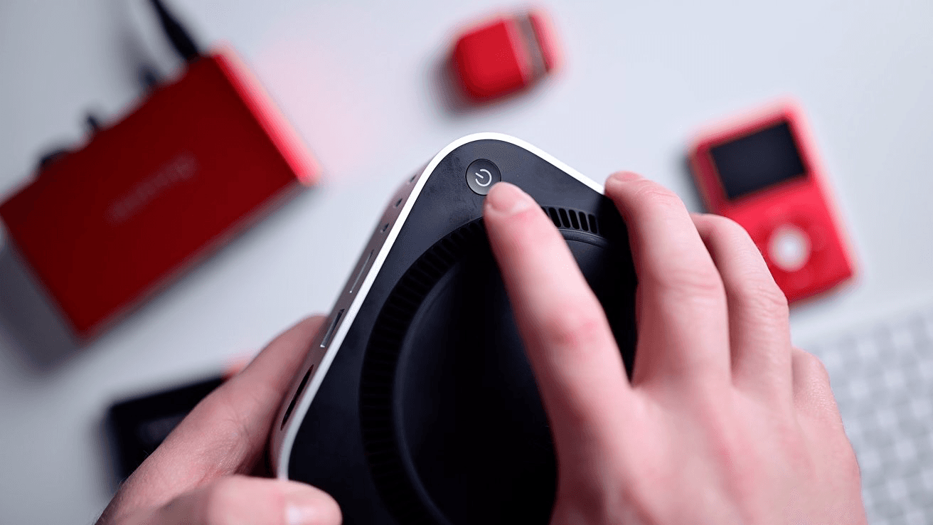 Person pressing on the start button of a m4 mac mini