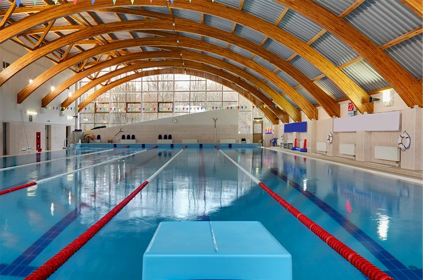 An indoor commercial swimming pool with marked lanes under a large arched wooden ceiling, representing municipal facility liability and negligence investigations by Schwinghamer Law in Stockton.
