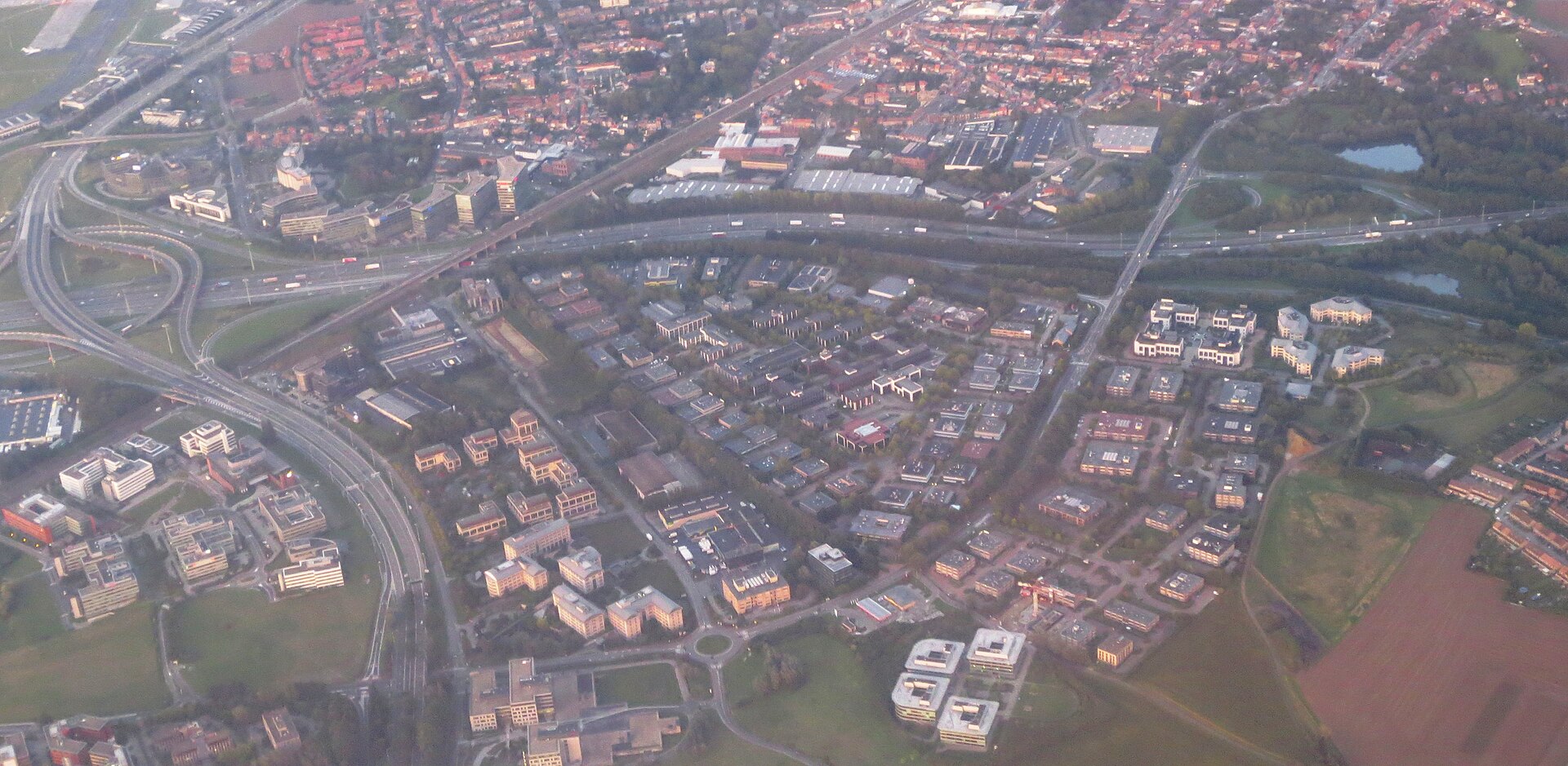 Luchtbeeld van het bedrijventerrein van Machelen-Diegem bij Brussels Airport, met rijen kantoorgebouwen en magazijnen langs de autosnelweg.