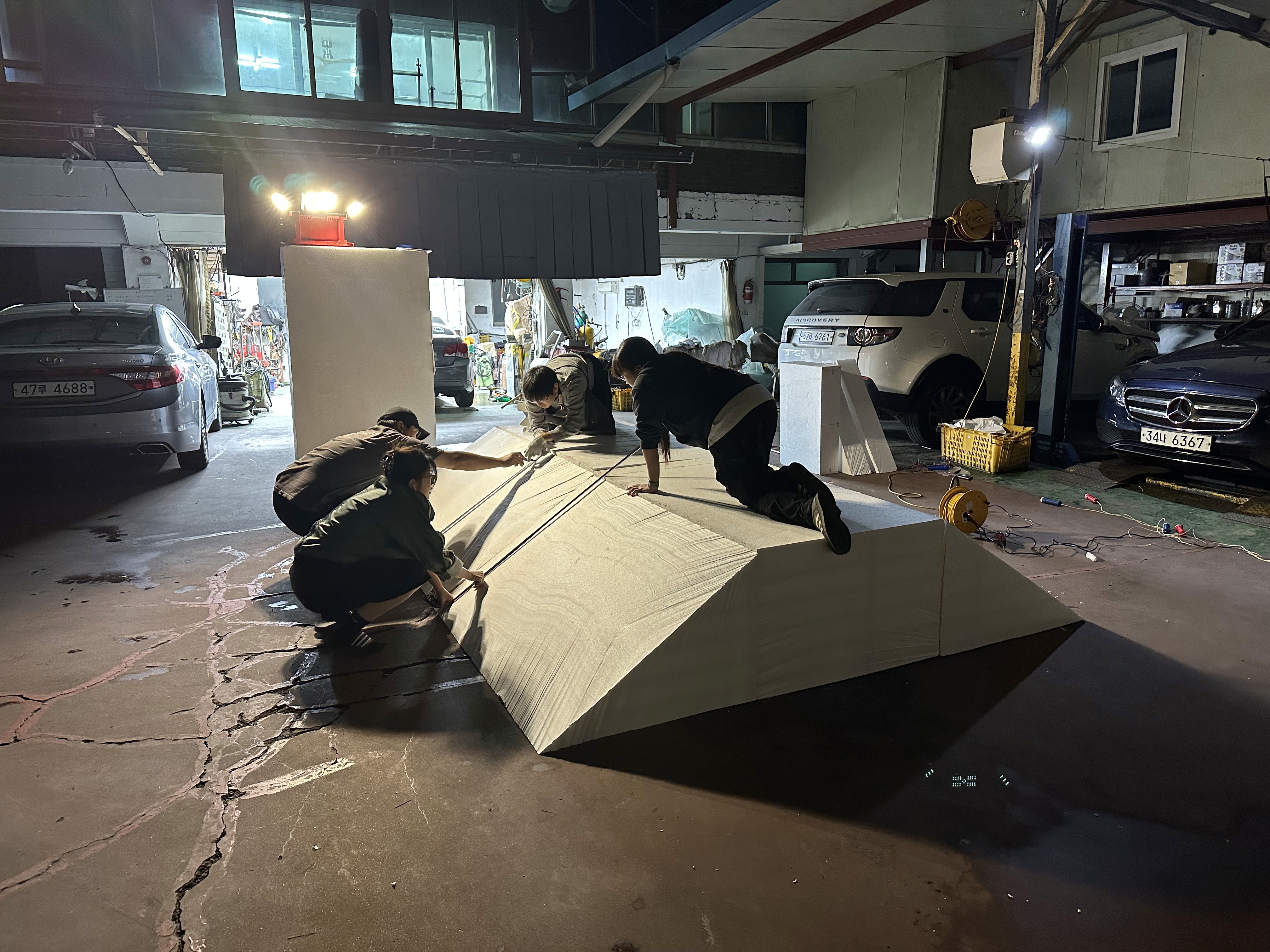 야간 현장 설치 작업 중인 산맥 지형 조형물, 스티로폼 구조체 위 시멘트 마감 전 / Nighttime on-site installation of the terrain sculpture before cement finishing