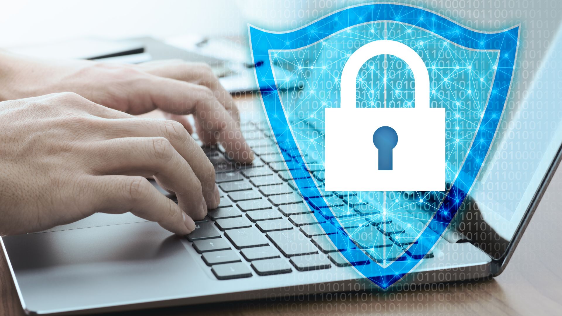 A blue shield with a lock icon overlayed on a laptop keyboard, representing cybersecurity.