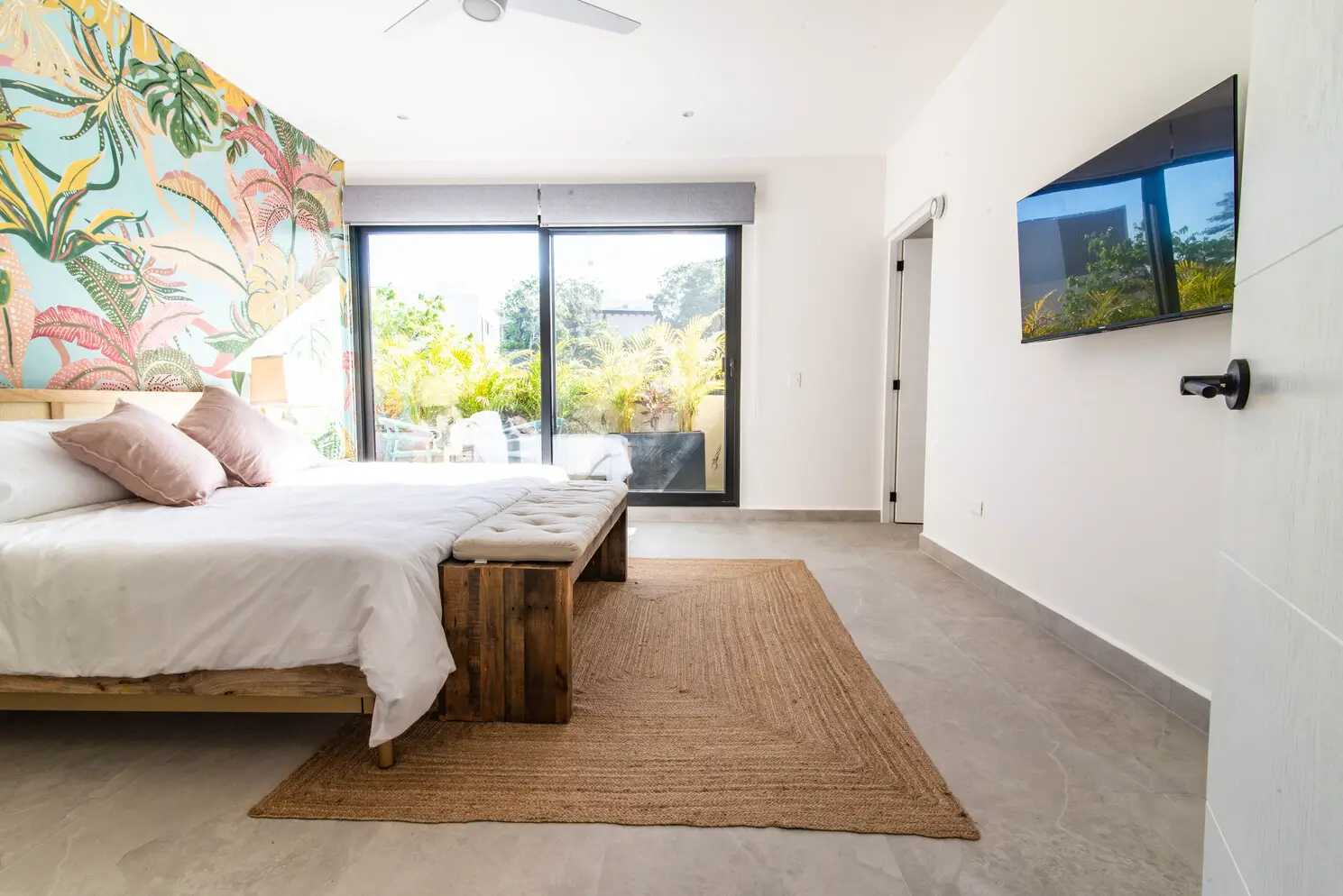 A bedroom in our rental in Playa del Carmen with subtle white walls and a caribbean wallpaper.