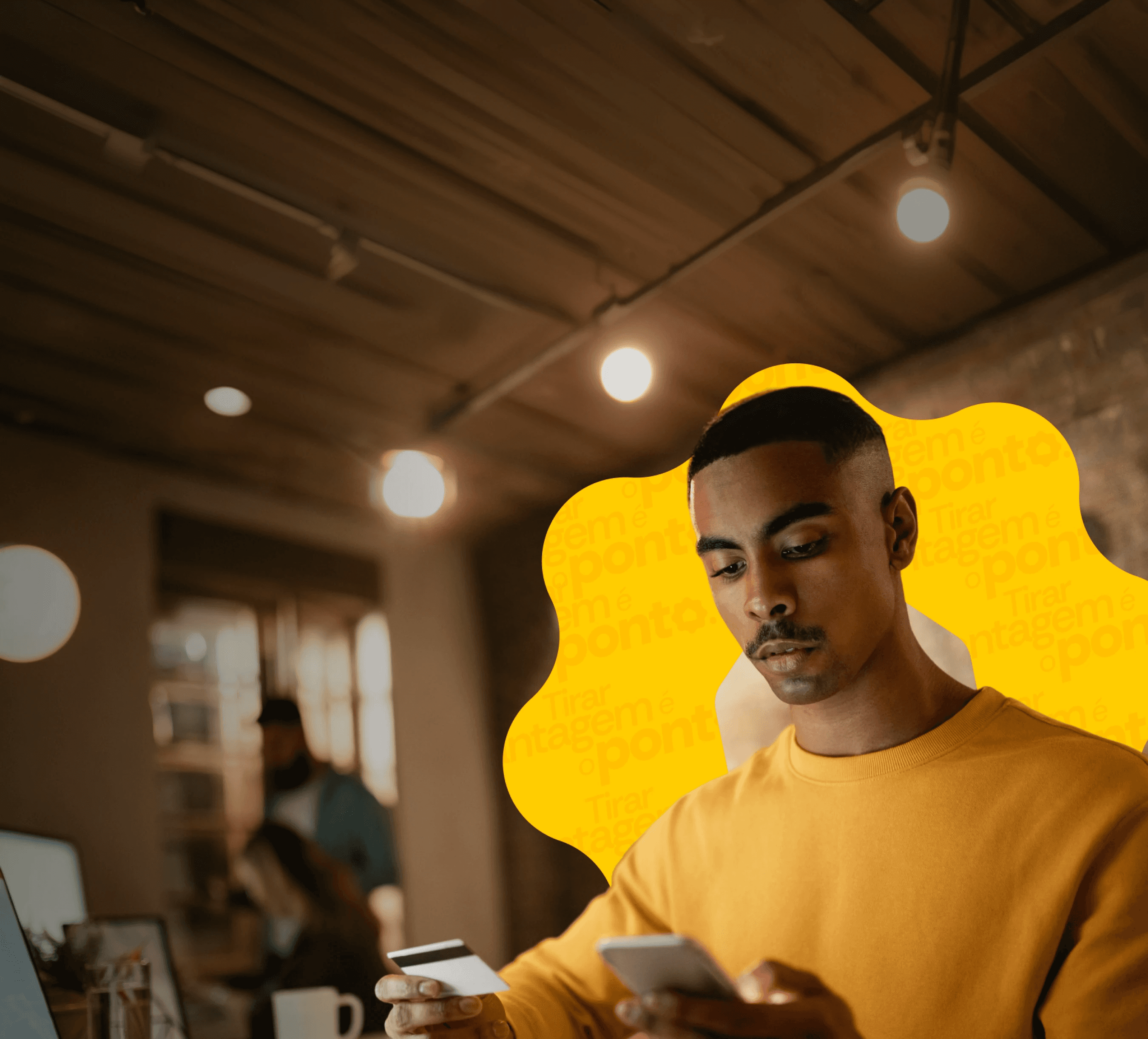 Homem jovem usando o celular e segurando um cartão de crédito