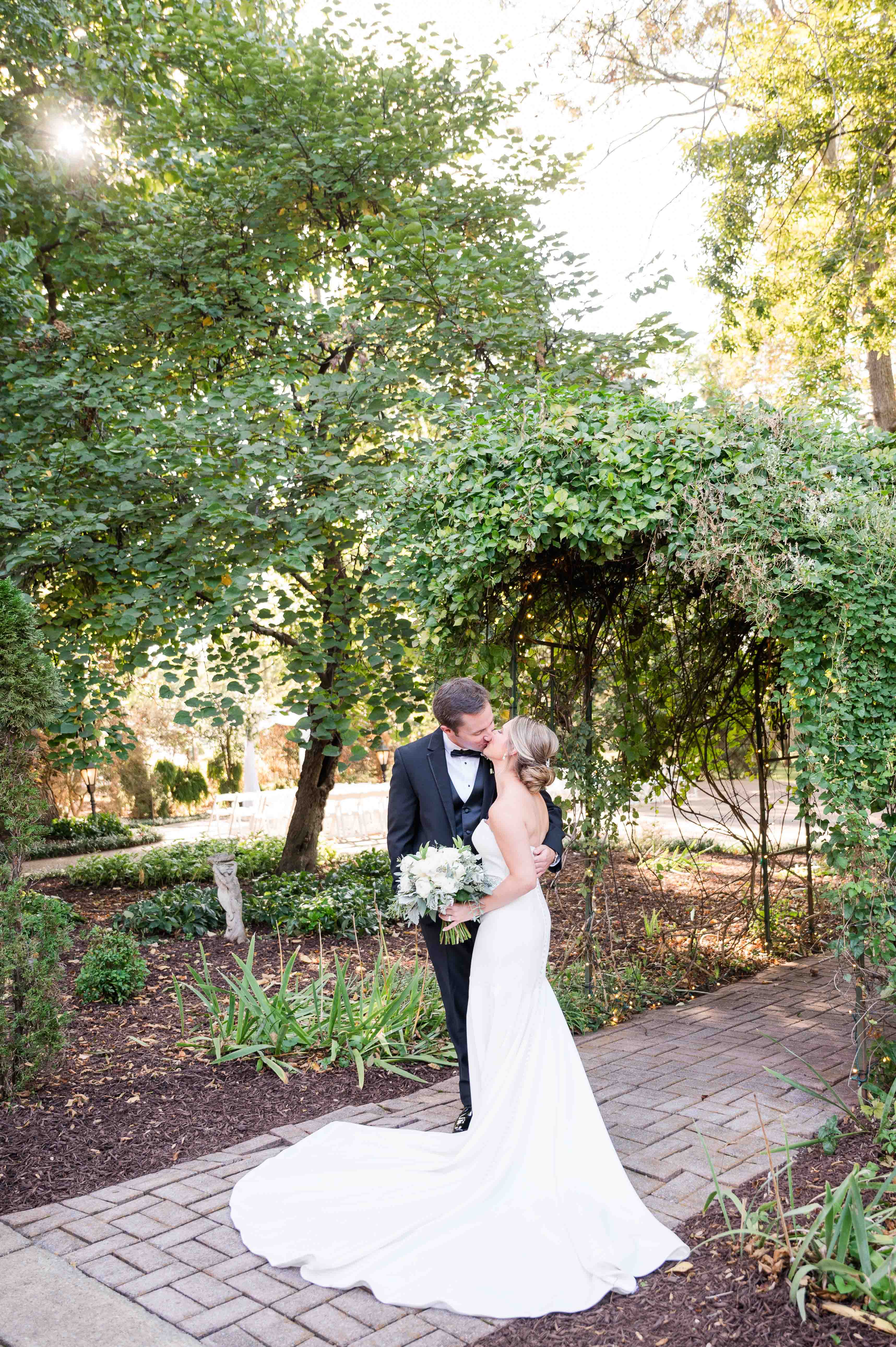 Outdoor bride and groom portrait underneath a garden arbor at Riverwood Mansion in Nashville, Tennessee.
