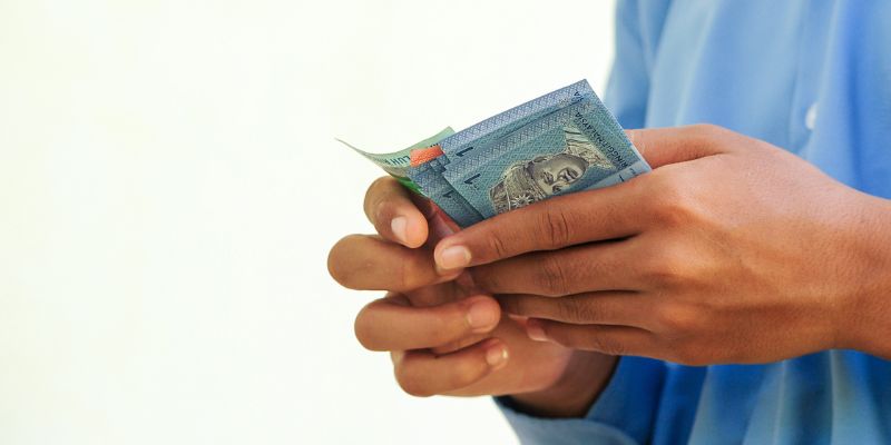 A man counting Malaysian ringgit