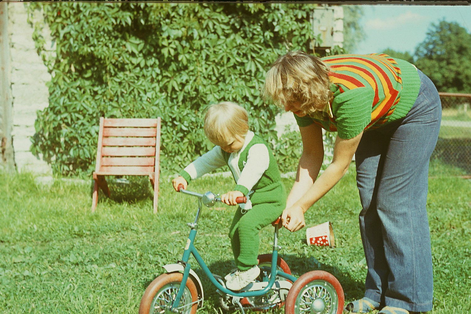Naine õpetab last rattaga sõitma