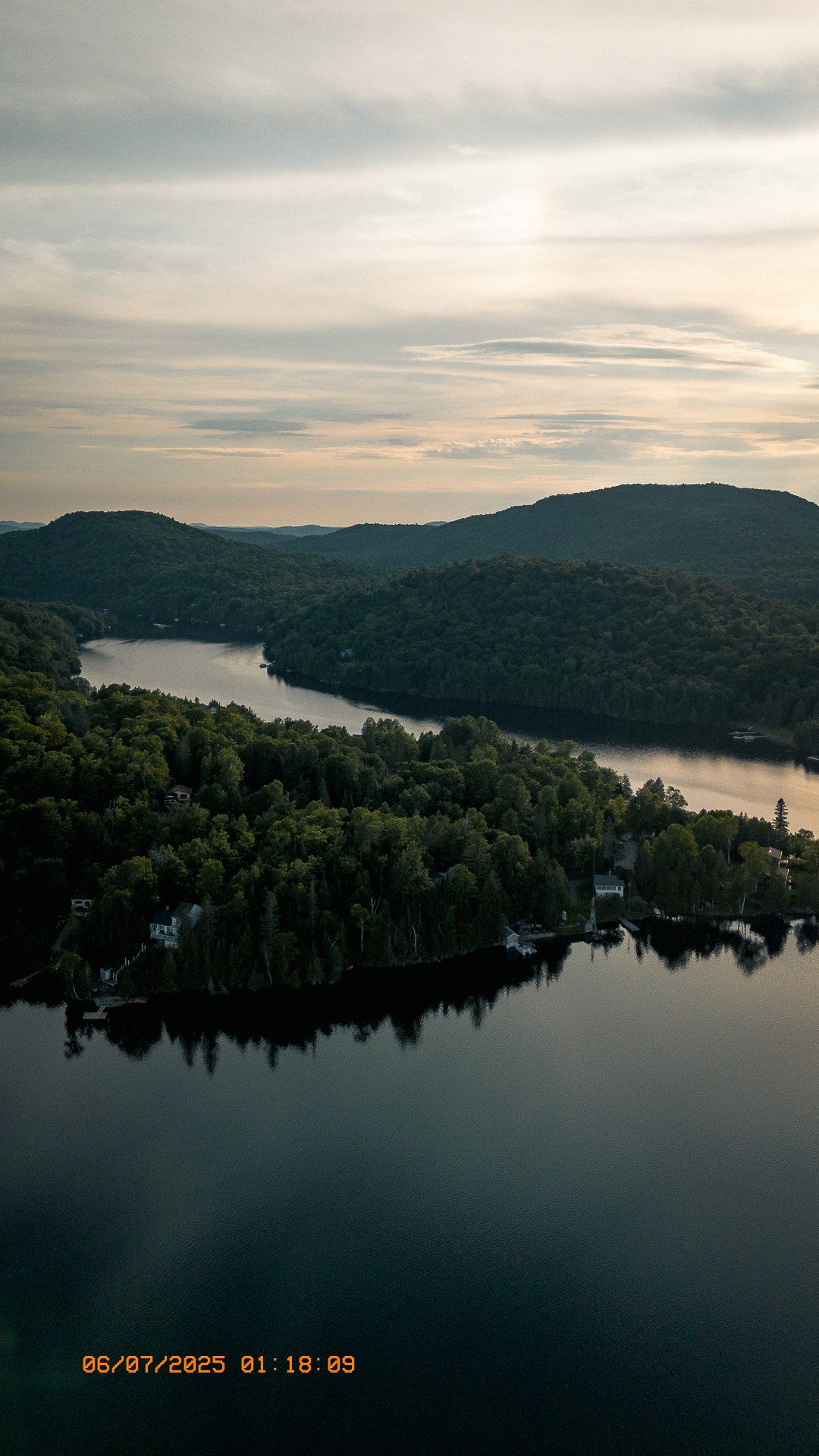 Vue aérienne du lac Laurel entouré de forêts et collines au coucher du soleil.