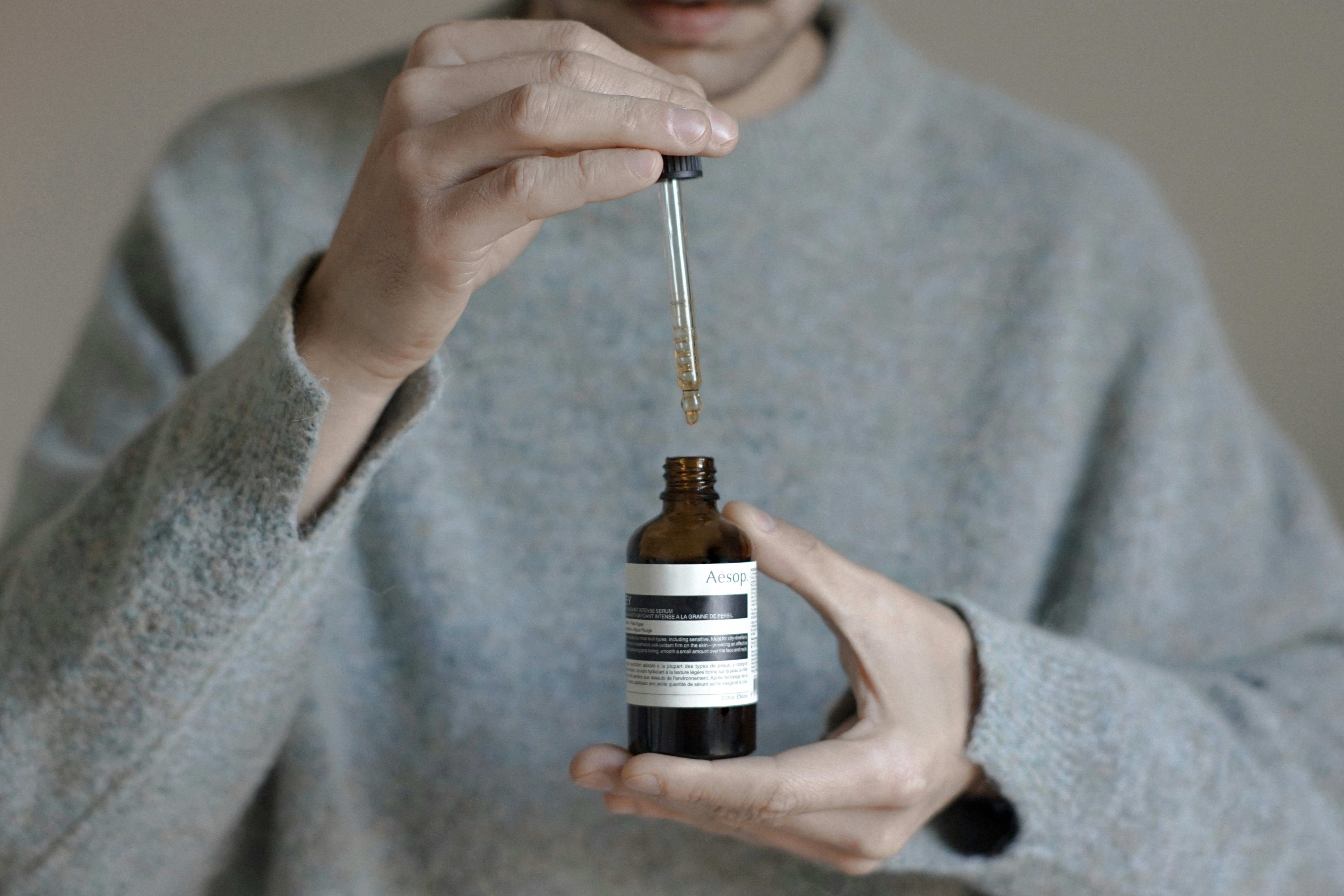 a person holding a bottle with a dropper
