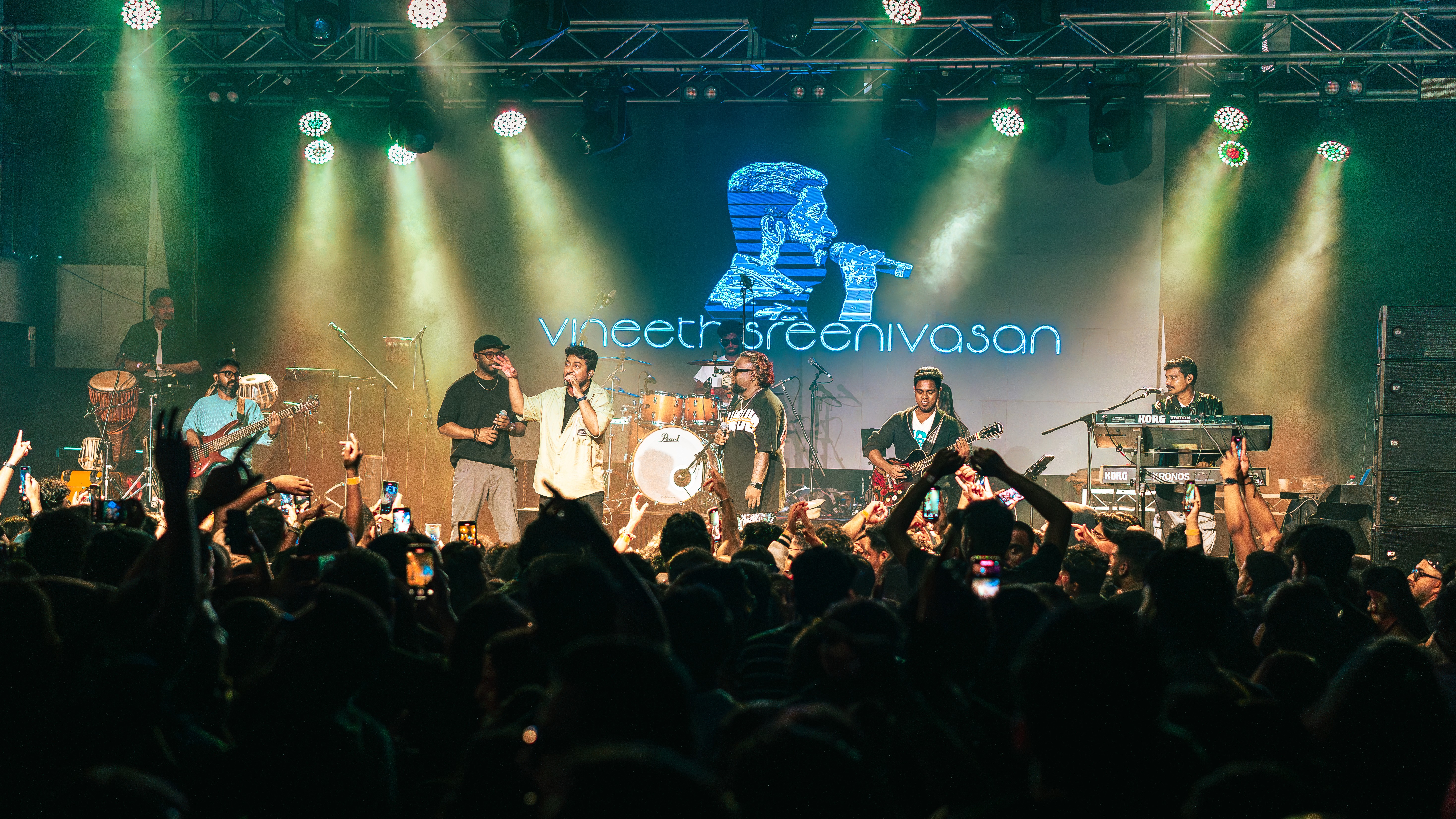 Palm trees and crowded beach with ocean in background.
