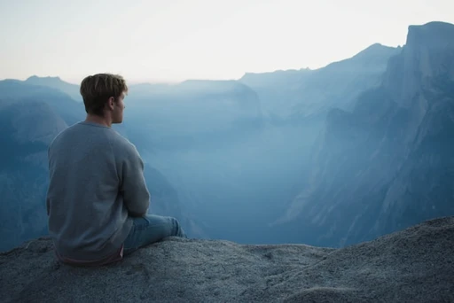 Man standing on a mountain overlook at sunrise, symbolizing planning ahead to avoid midweek stress and burnout.